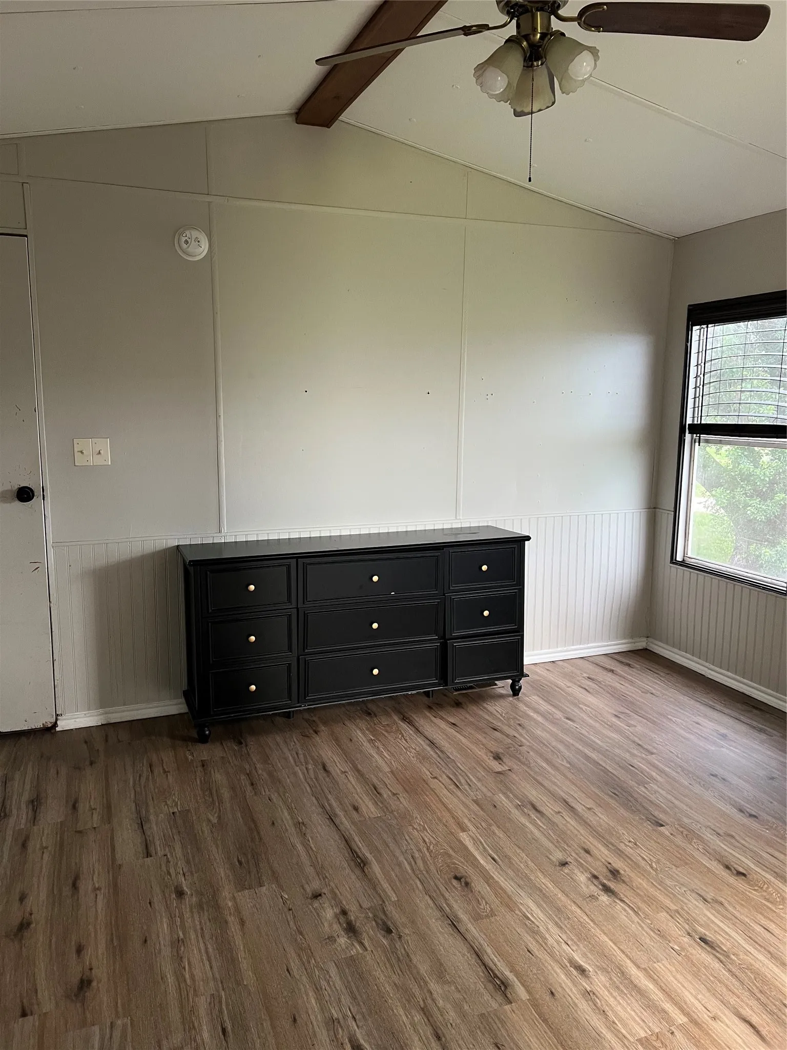 This room features wood-look flooring and a ceiling fan with light fixture