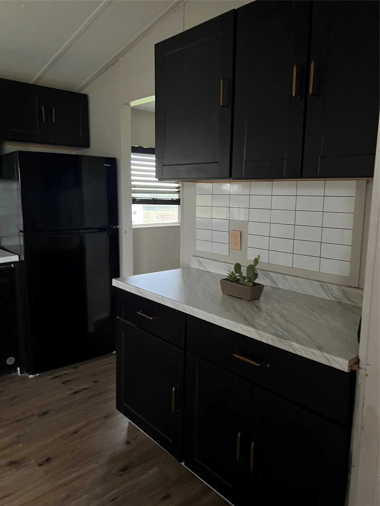 The kitchen features dark cabinetry, white countertops, a white subway tile backsplash, and dark flooring