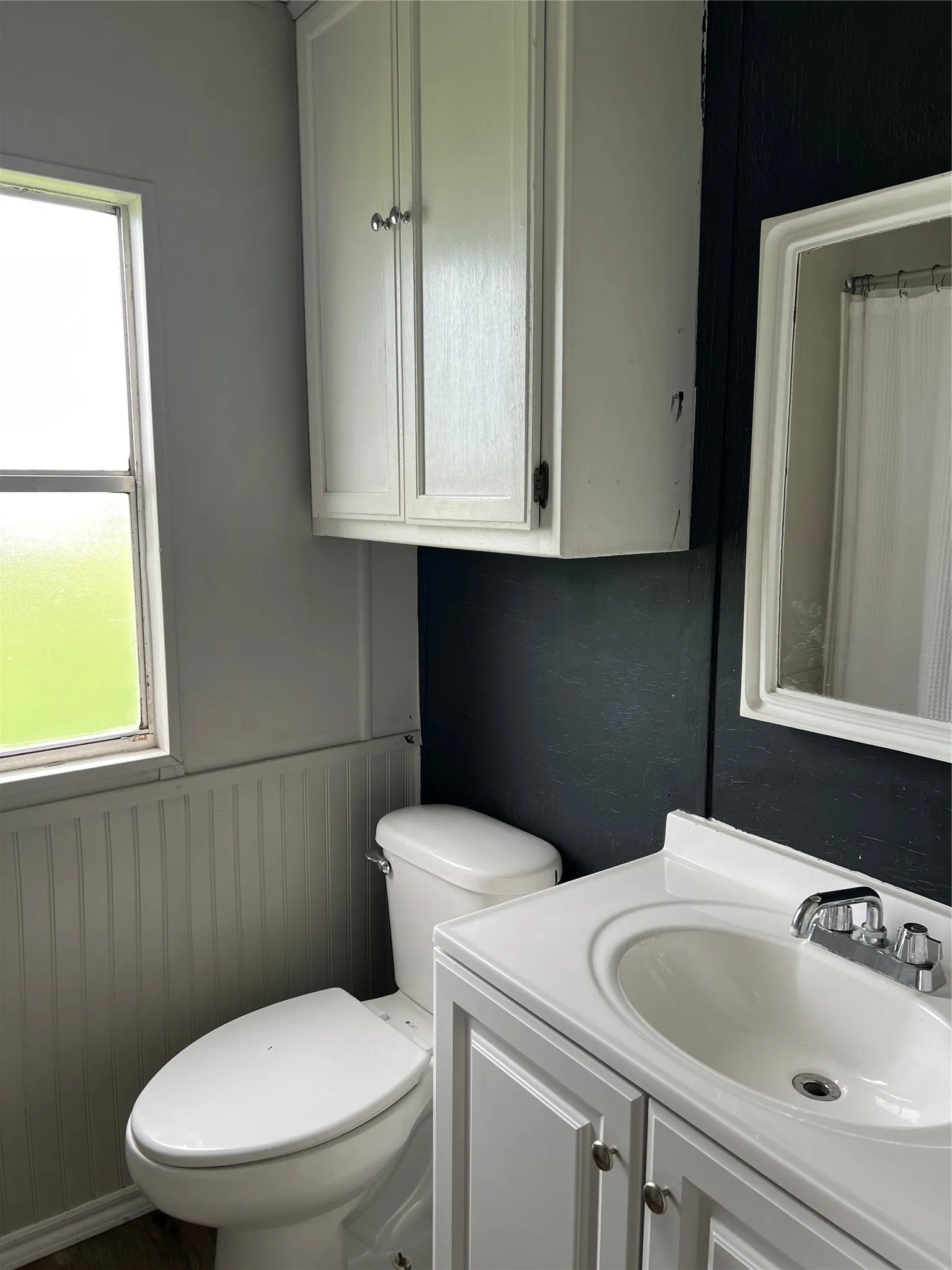 Bathroom featuring a white vanity with an integrated sink, a mirror, and a white toilet