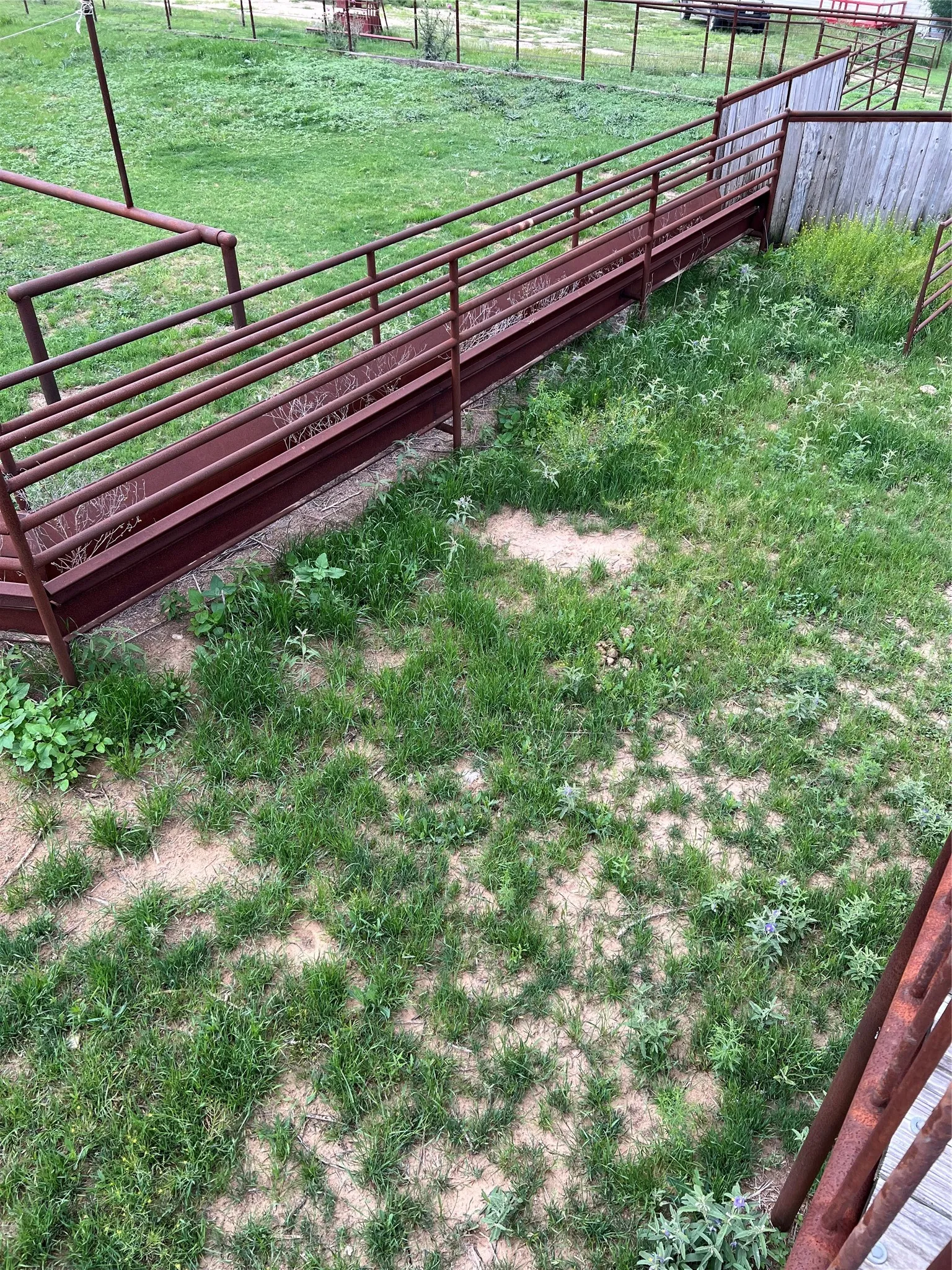 The property features a sloped metal ramp with railings and a wooden wall, set within a grassy area