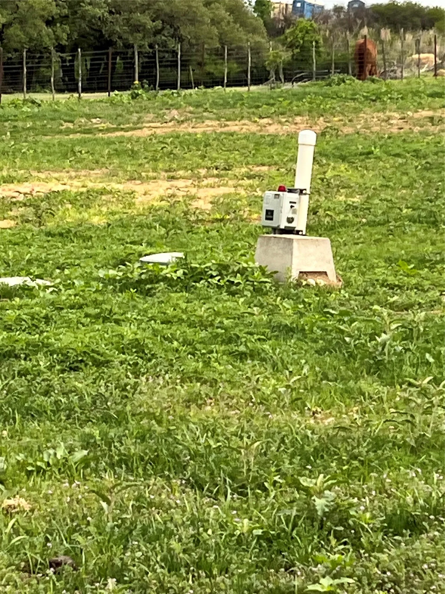 Expansive open land featuring green vegetation and an installed utility fixture