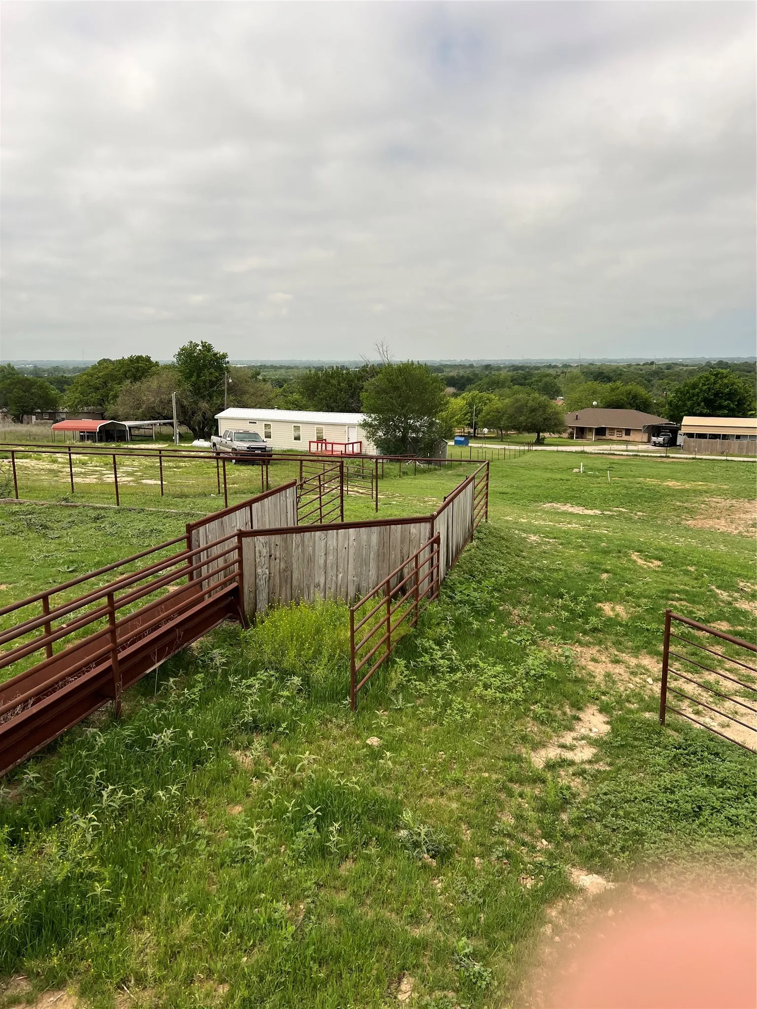 The property features expansive grassy grounds, a brown metal fence, and a wooden fence structure
