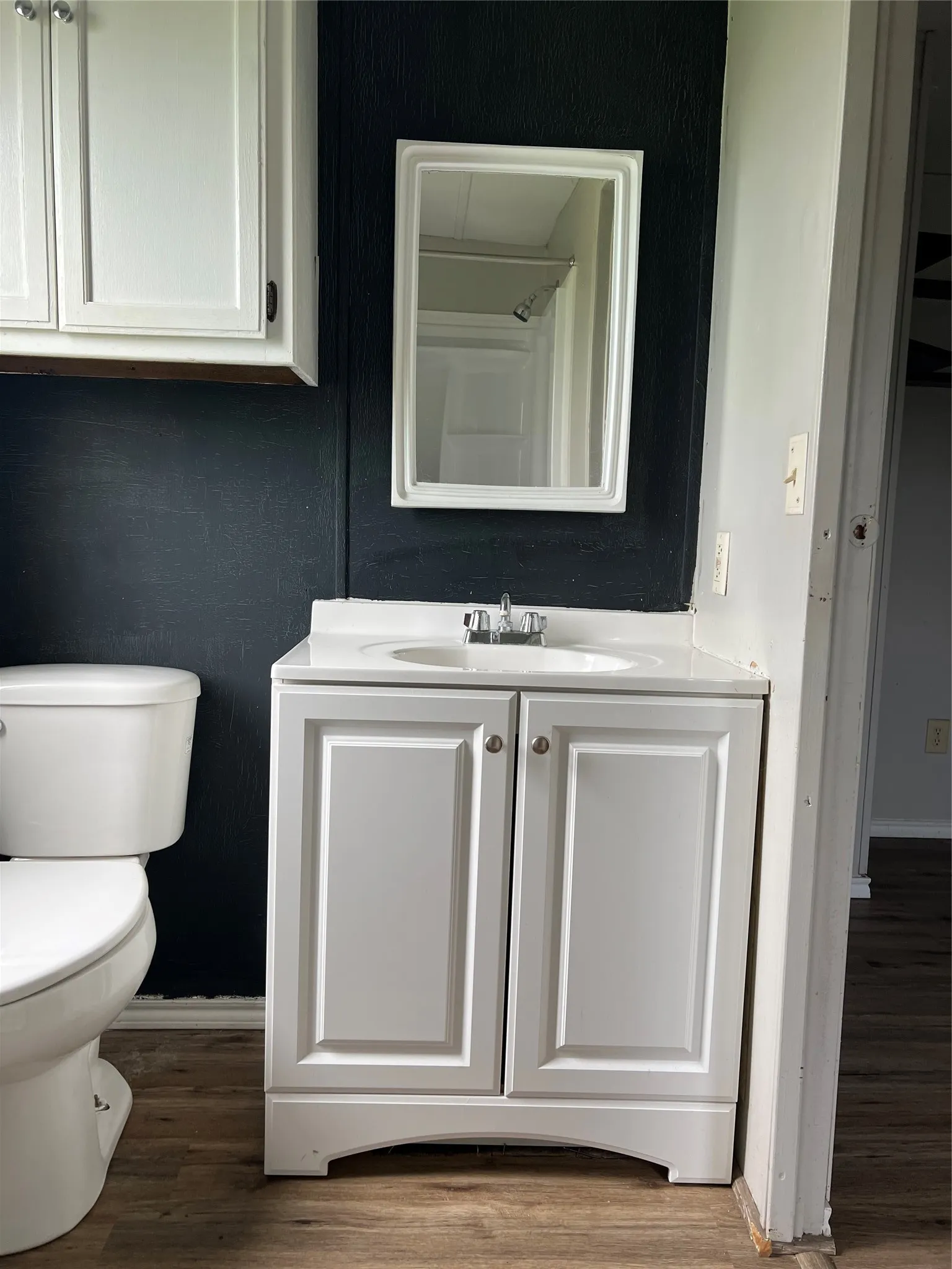 The bathroom features a white vanity with a built-in sink and a mirror above, complemented by a white toilet