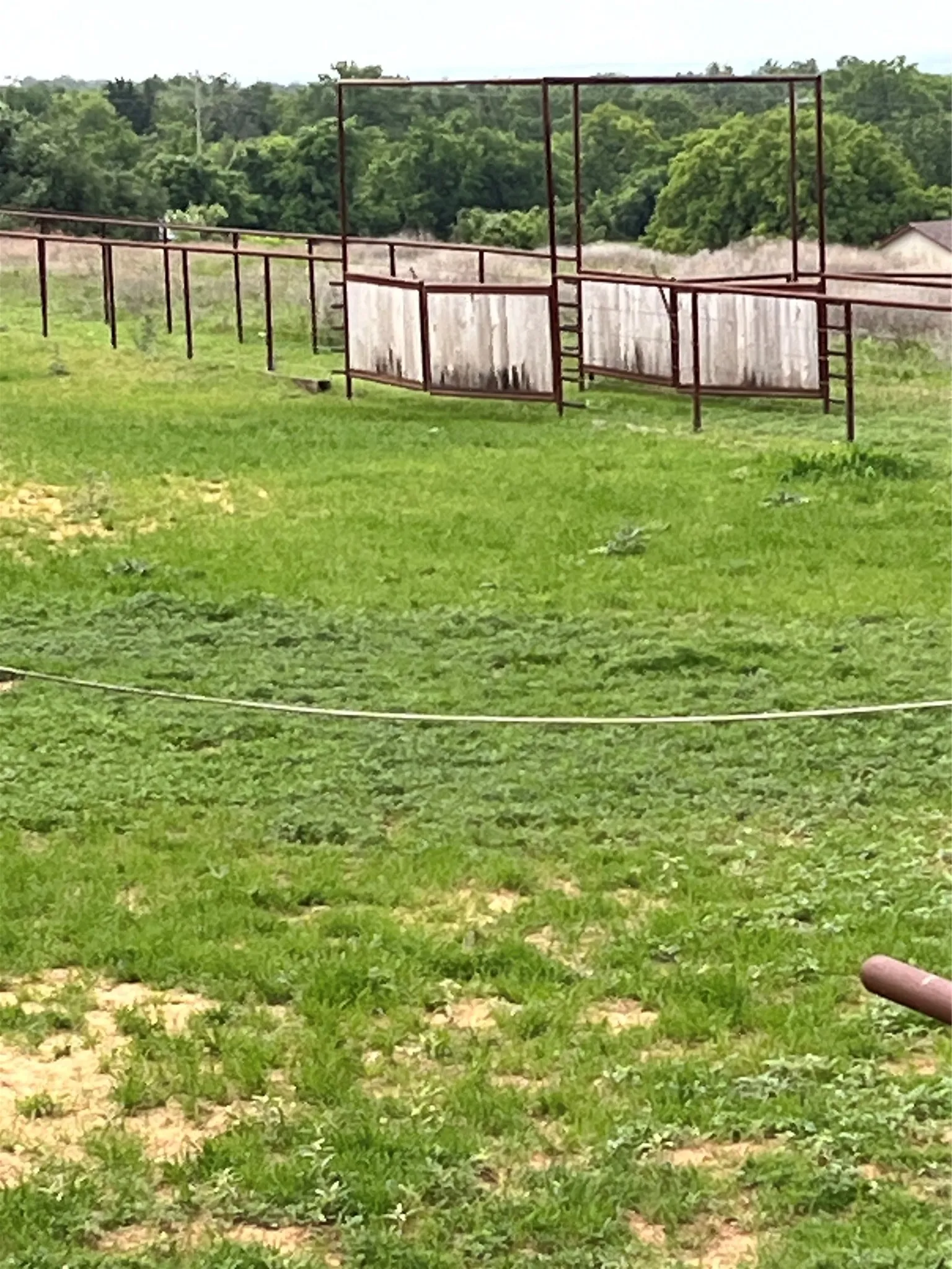 The property features an extensive grassy area with a partial fence structure visible