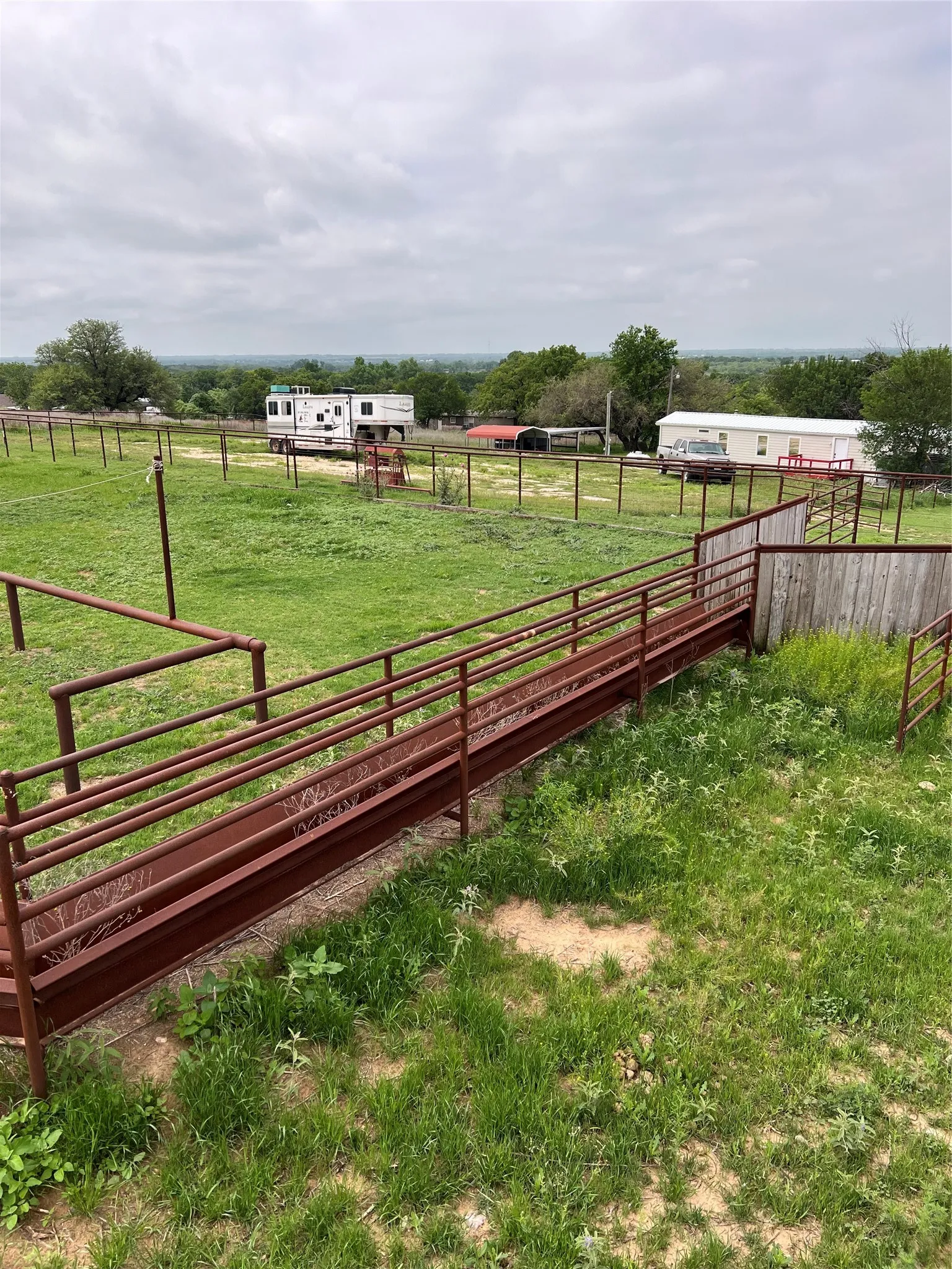 The property features extensive green space, a metal fence, and a long, rust-colored ramp structure