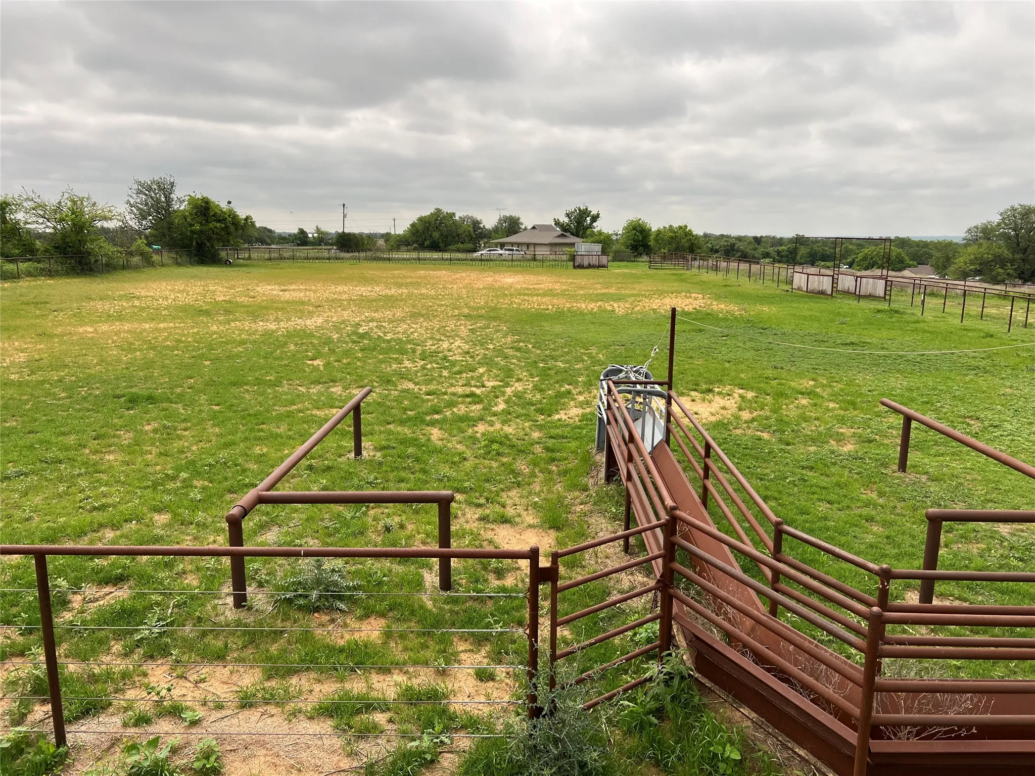 Expansive outdoor area featuring green grass and a system of metal fencing