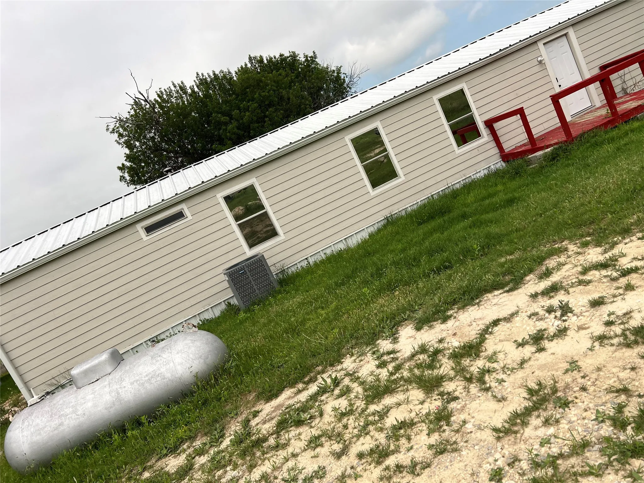 The property features a light-colored exterior siding, a white metal roof, and a red deck