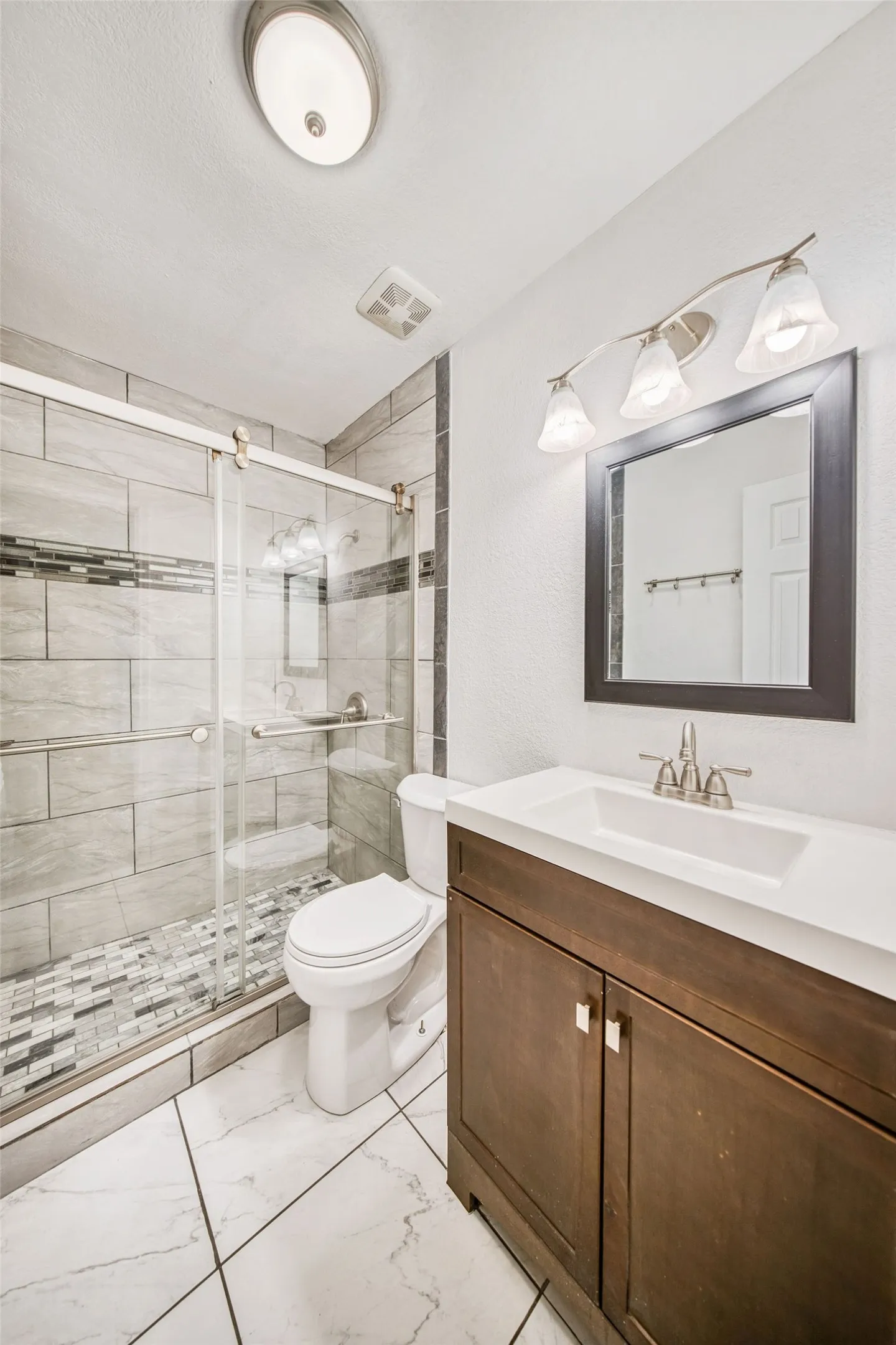 This bathroom features a contemporary vanity with a white countertop and a rectangular sink, complemented by a large mirror with a dark frame