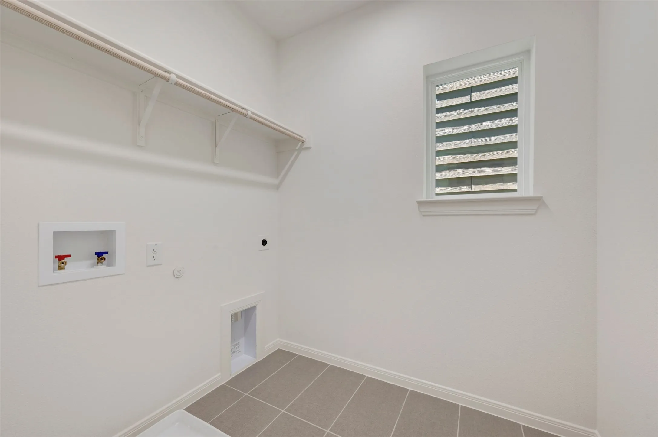 Laundry area featuring tile flooring, a mounted window, and built-in shelving