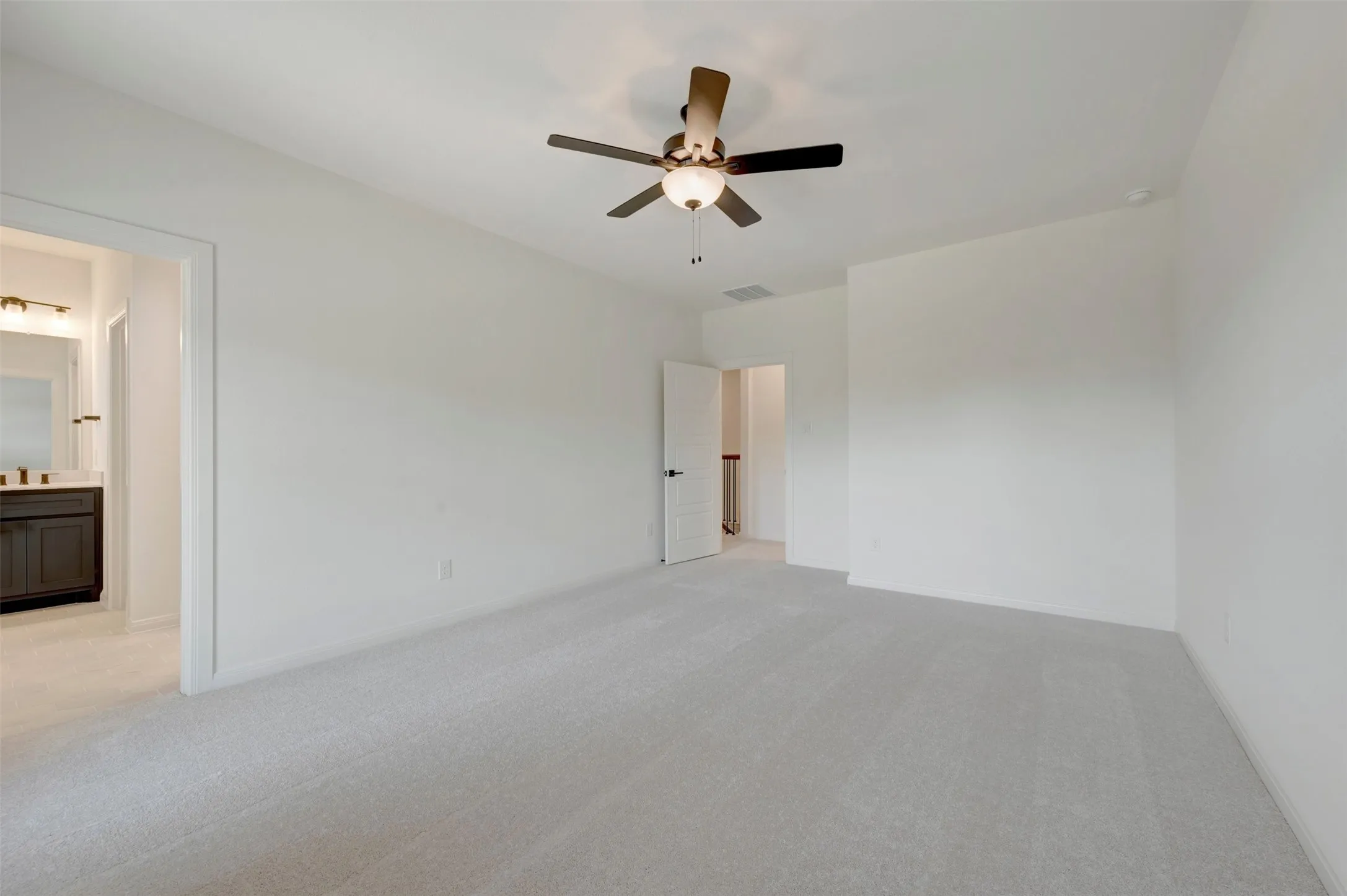 Spacious room with light-colored carpeting, a ceiling fan with integrated lighting, and a neutral wall palette