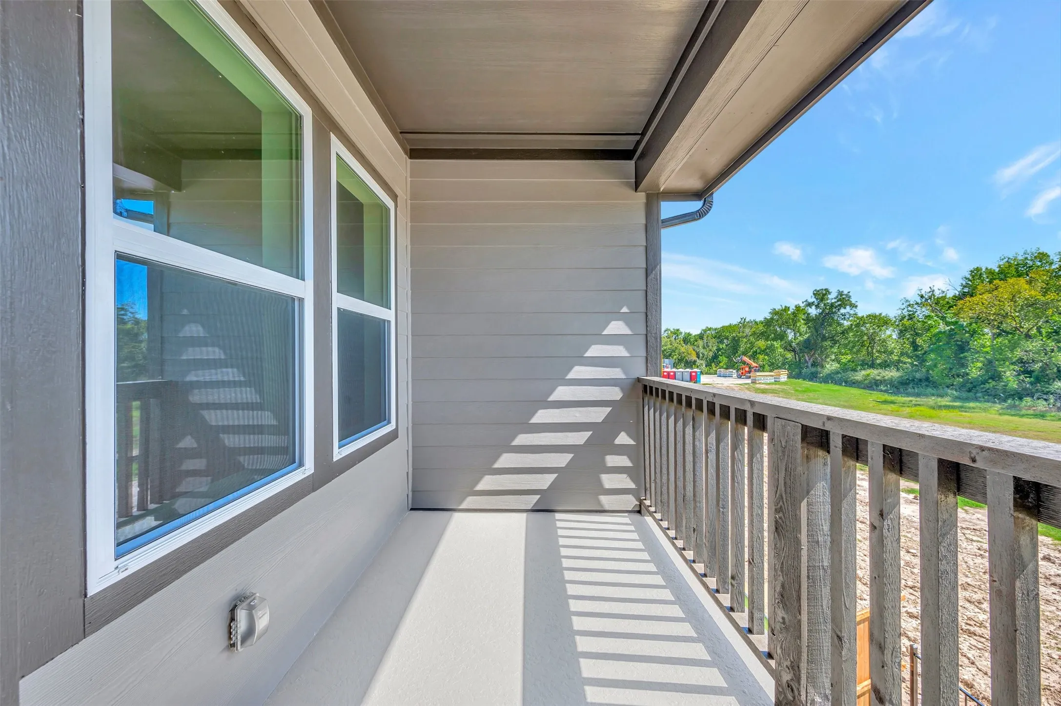 Private balcony with a wooden railing and an exterior electrical outlet