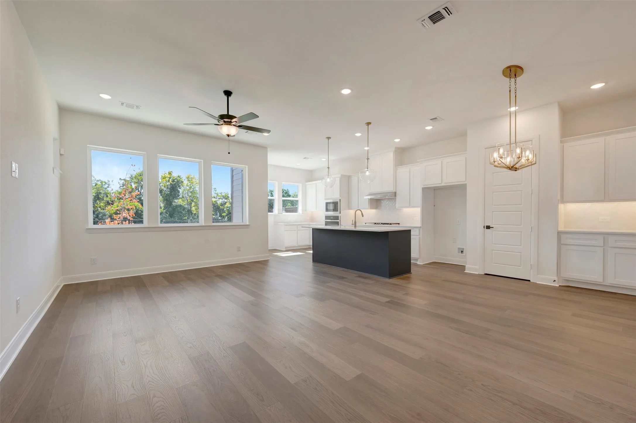 Open-concept living area with wood-finish flooring, recessed lighting, and a ceiling fan