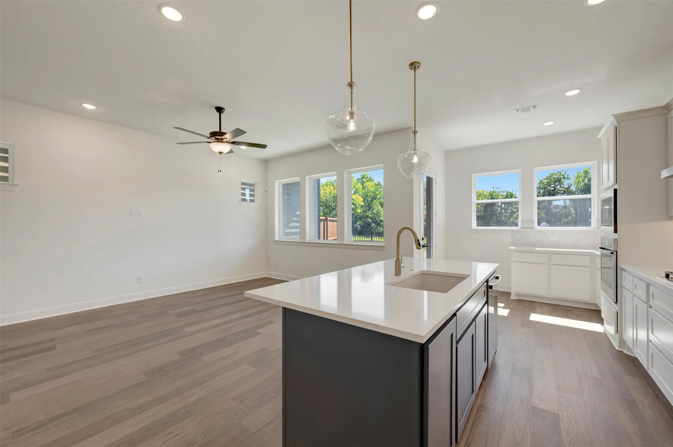 Spacious open-concept layout featuring wood-finish flooring, recessed lighting, and a contemporary ceiling fan