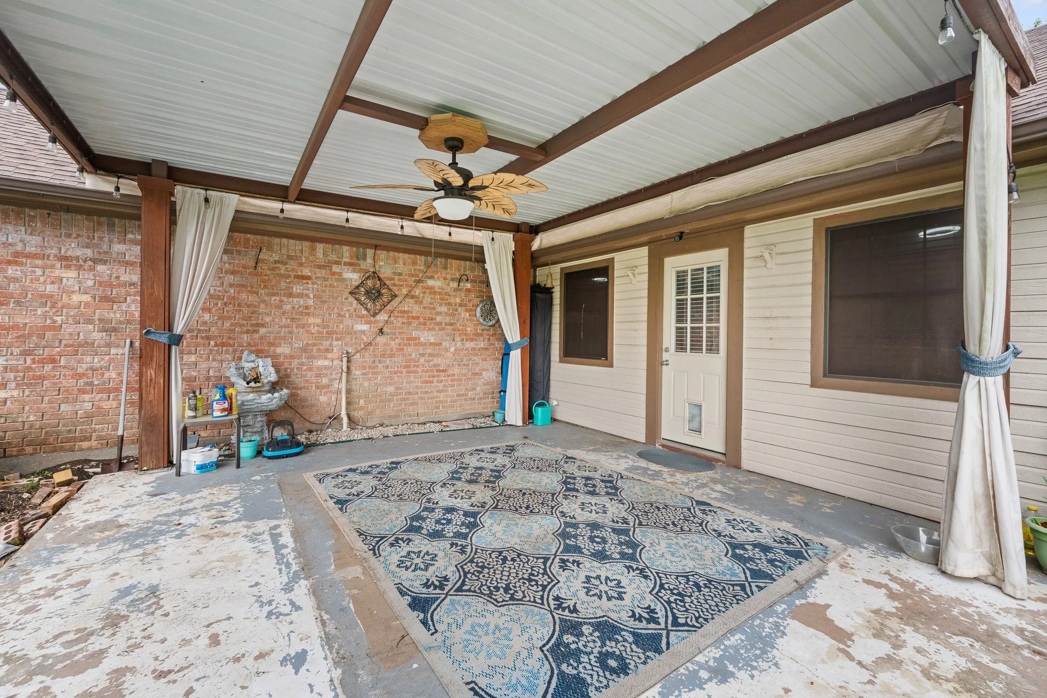 The property features a covered patio with a ceiling fan, offering a comfortable outdoor living space
