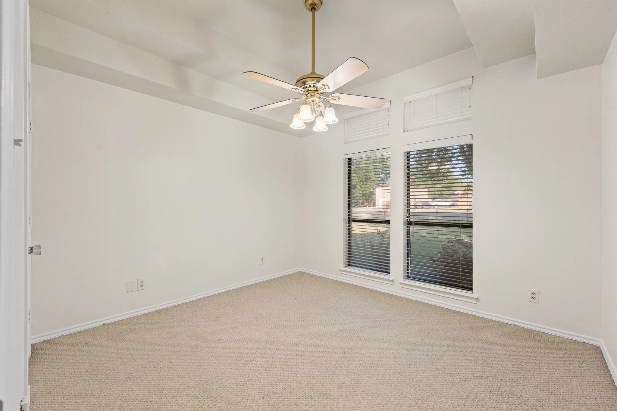 Tray ceiling with an overhead fan, carpeted flooring, and a large window with blinds