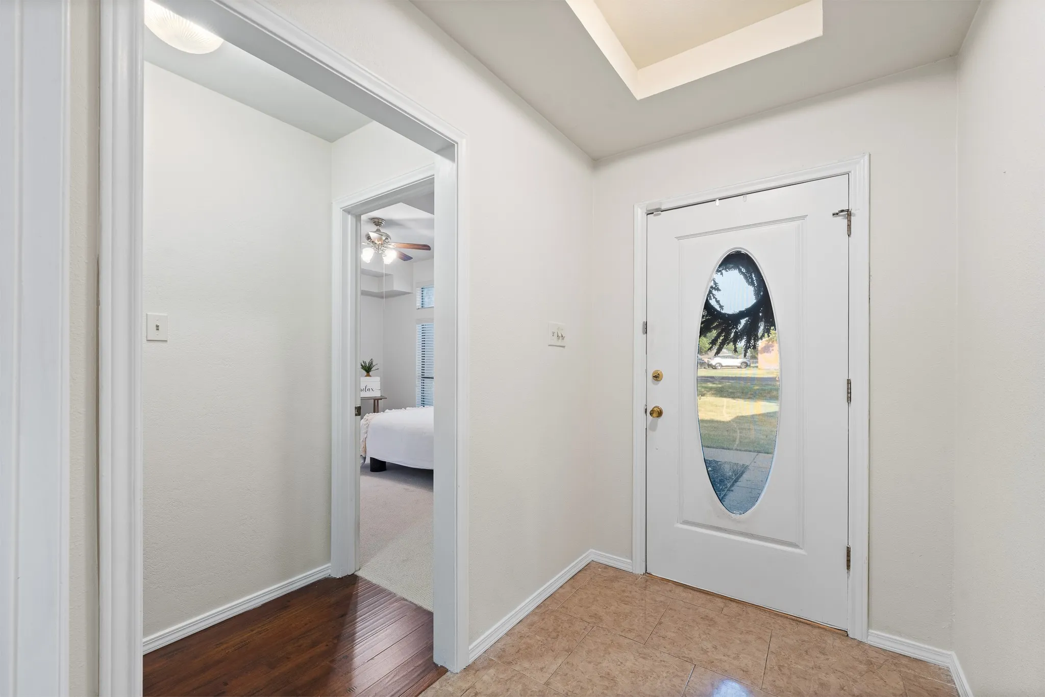 Entryway with a white paneled door featuring an oval glass insert, recessed ceiling light, and tile flooring