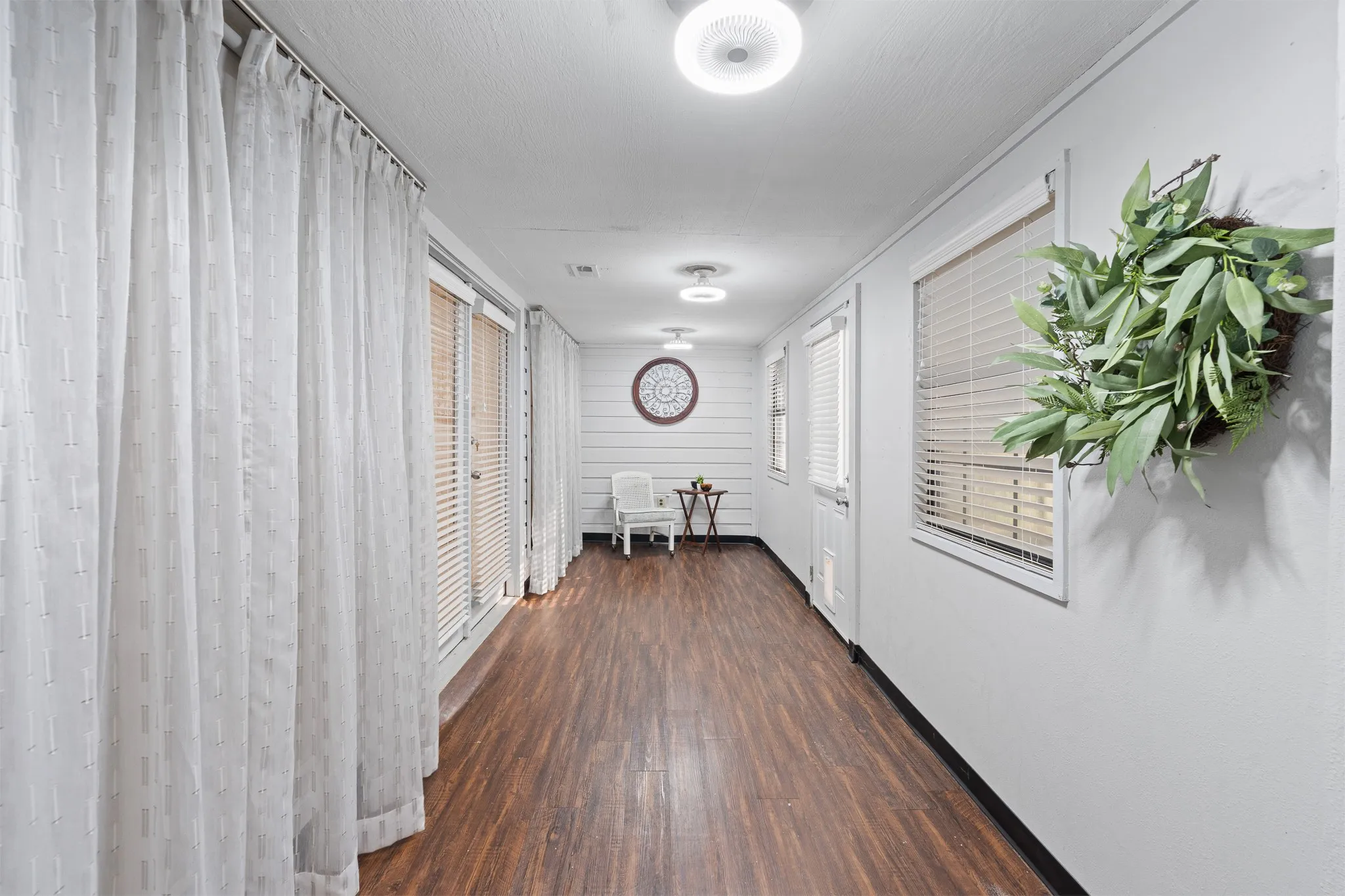 Wood-finish flooring, multiple windows with blinds, recessed lighting, and shiplap wall accent