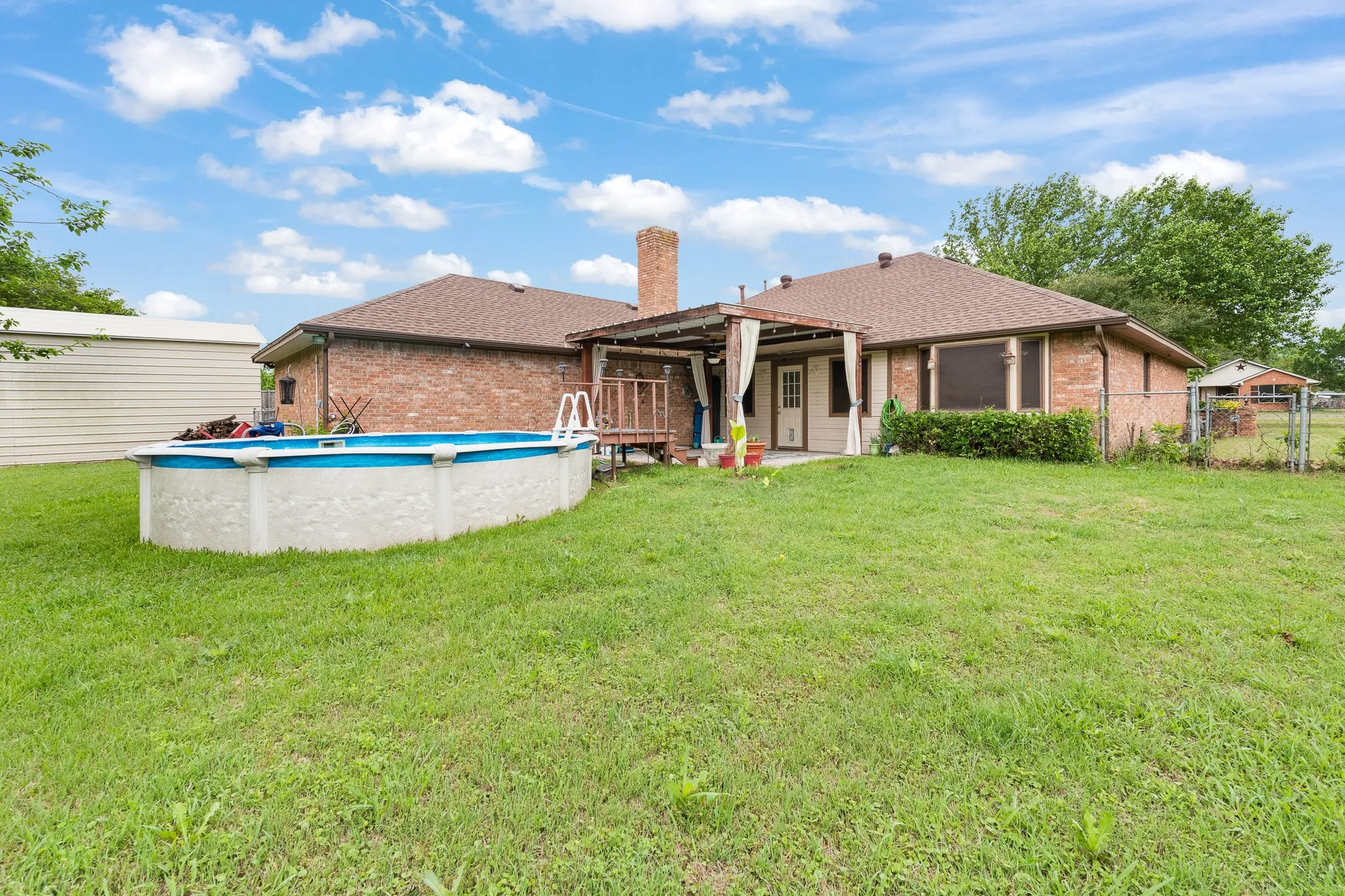 The property features a spacious rear yard with a lawn, an above-ground swimming pool, and a covered patio area
