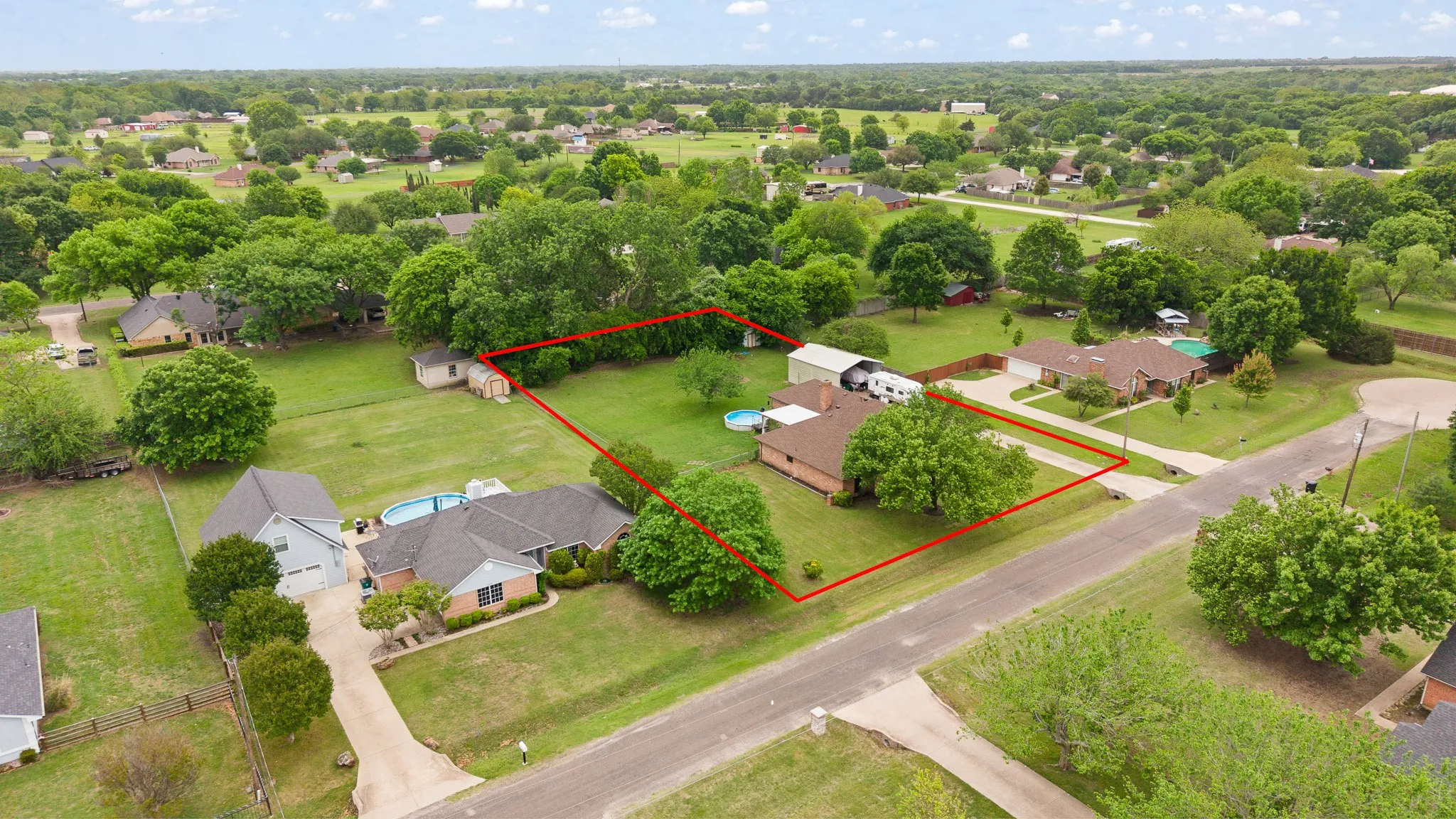 The property features a large yard with extensive green space and mature trees, along with a swimming pool