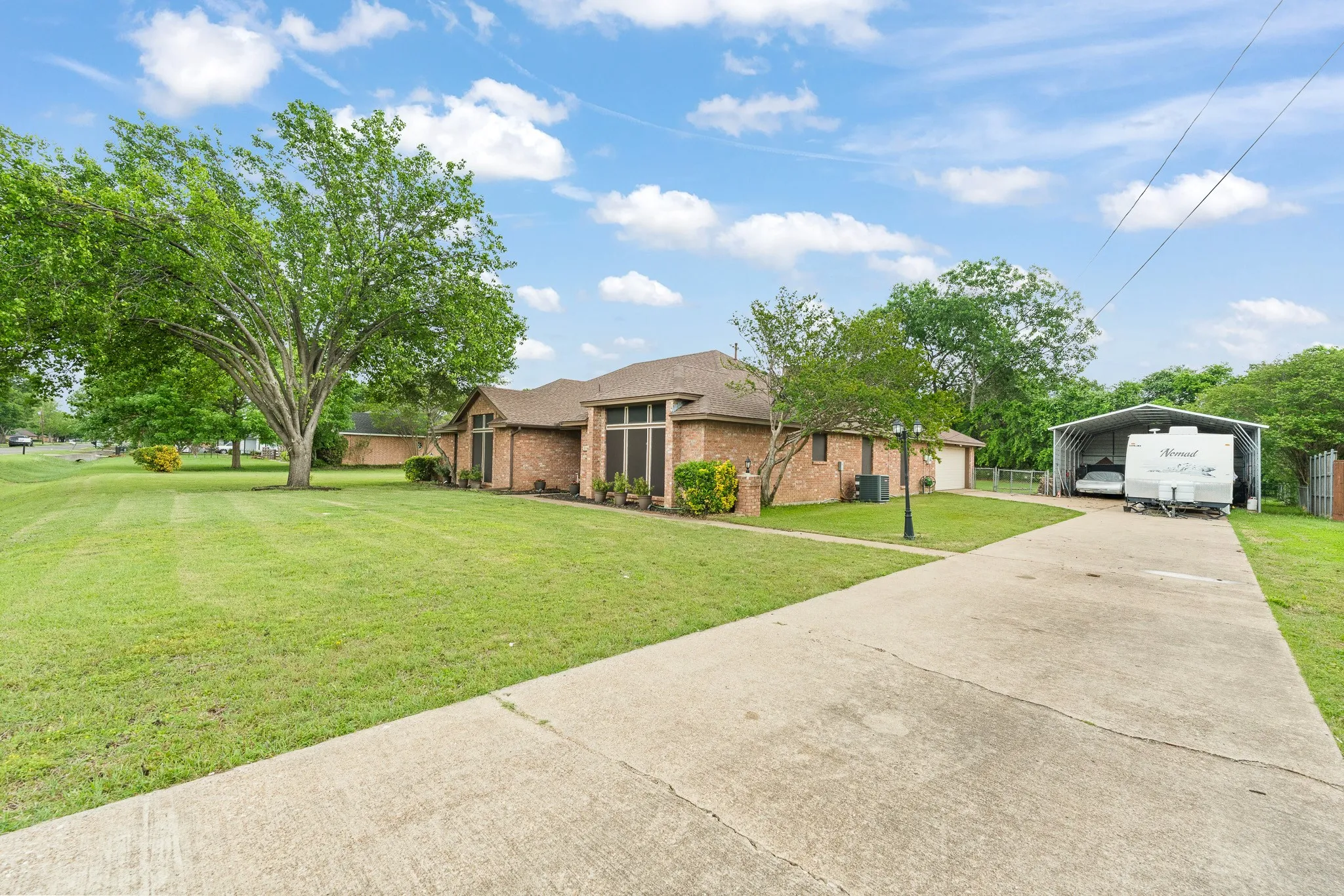 The property features a brick exterior, a concrete driveway, and an expansive lawn with mature trees