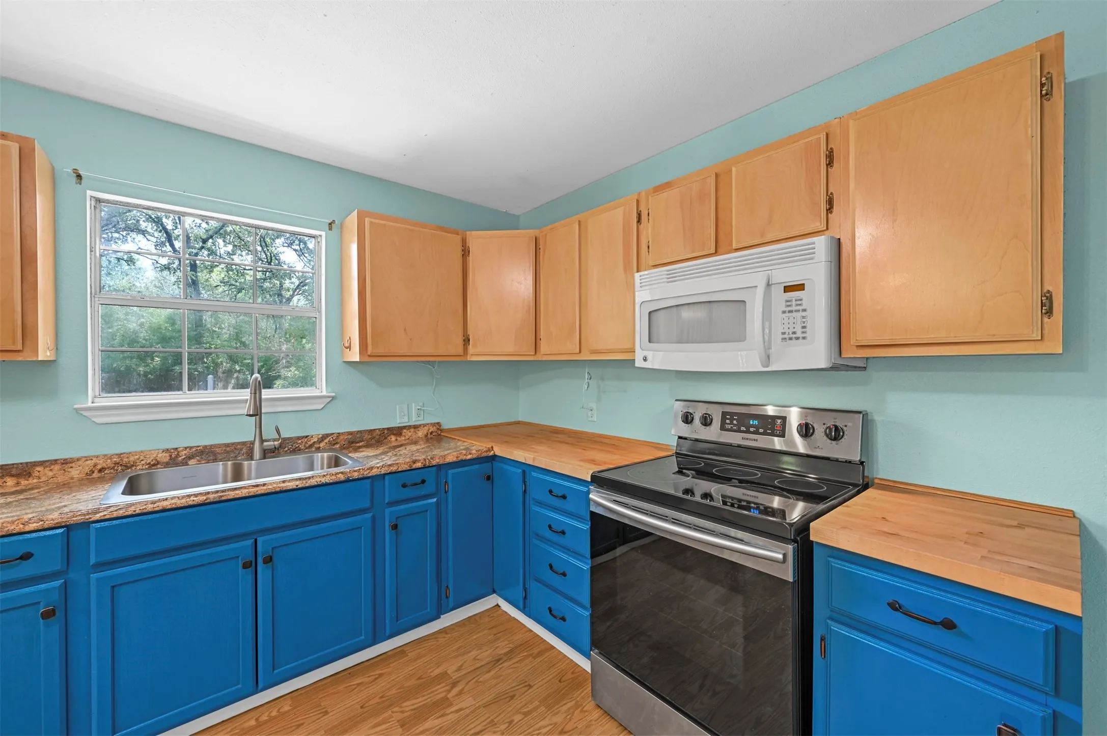 Kitchen featuring electric range, sink, light hardwood / wood-style floors, and wooden counters