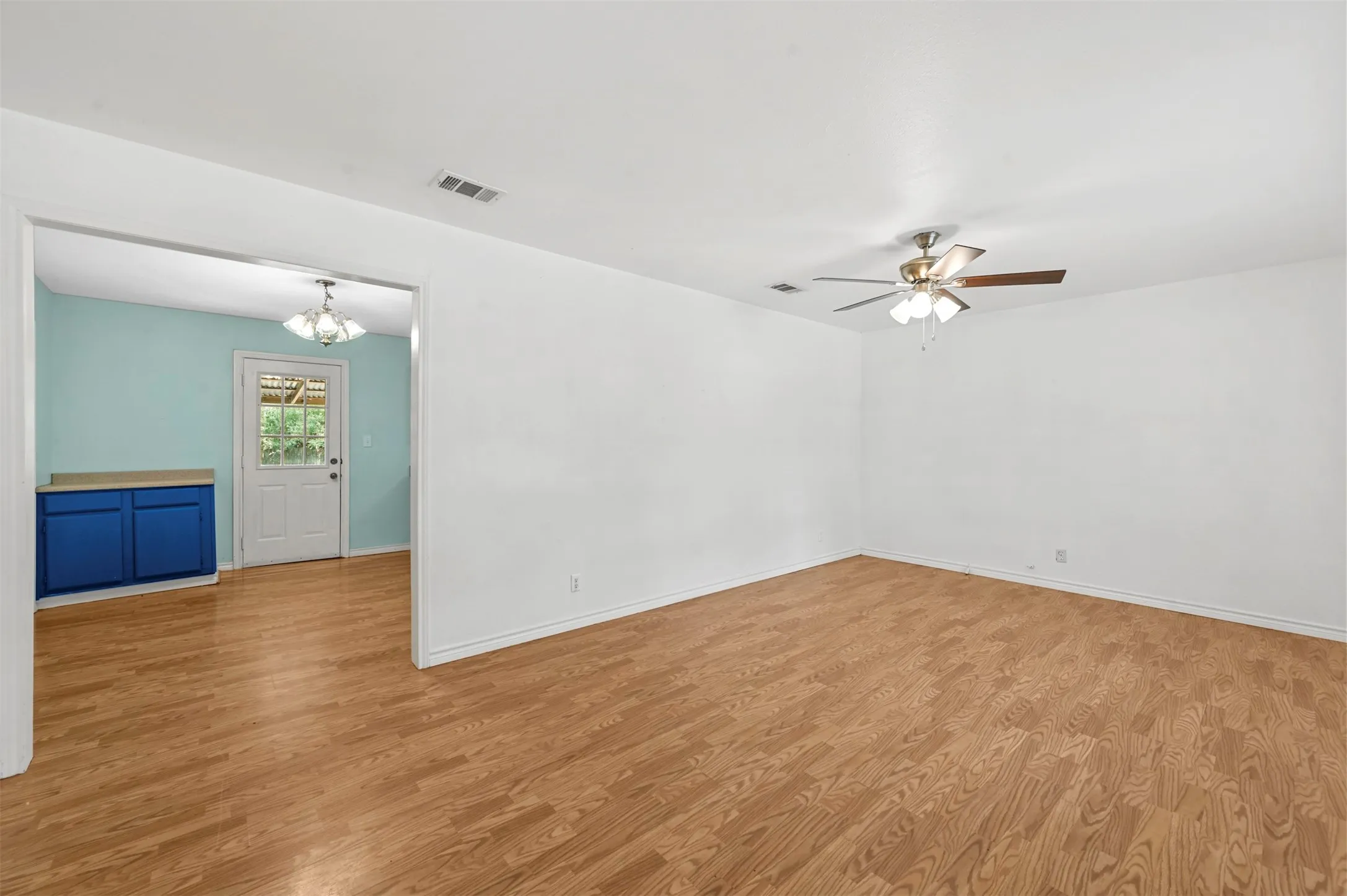 Unfurnished room with ceiling fan with notable chandelier and light hardwood / wood-style floors