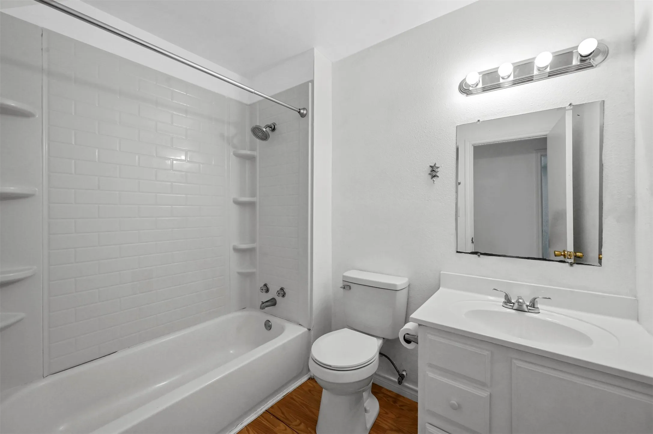 Full bathroom with vanity, toilet, hardwood / wood-style floors, and tiled shower / bath