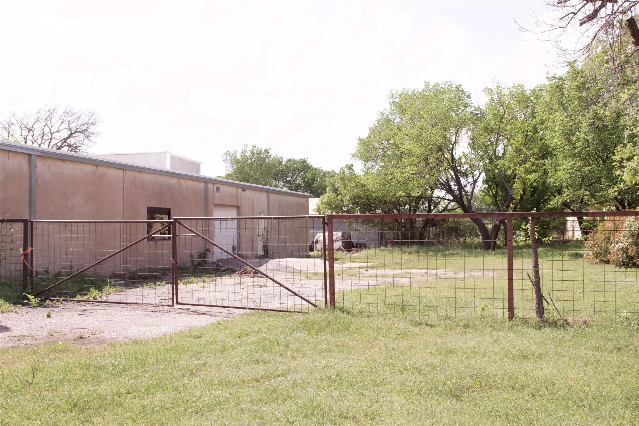 The property features a concrete block building with a white door and a small window, set behind a wire fence with a gate