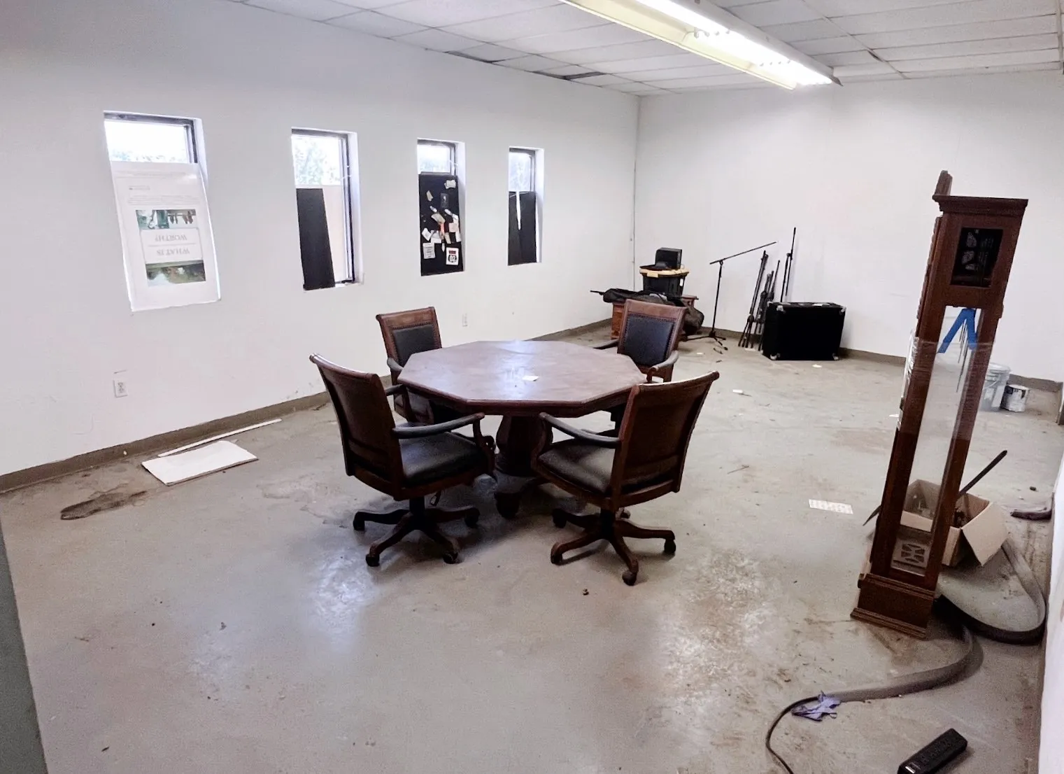 This spacious room features white painted walls, a light-colored floor, and several windows providing natural light