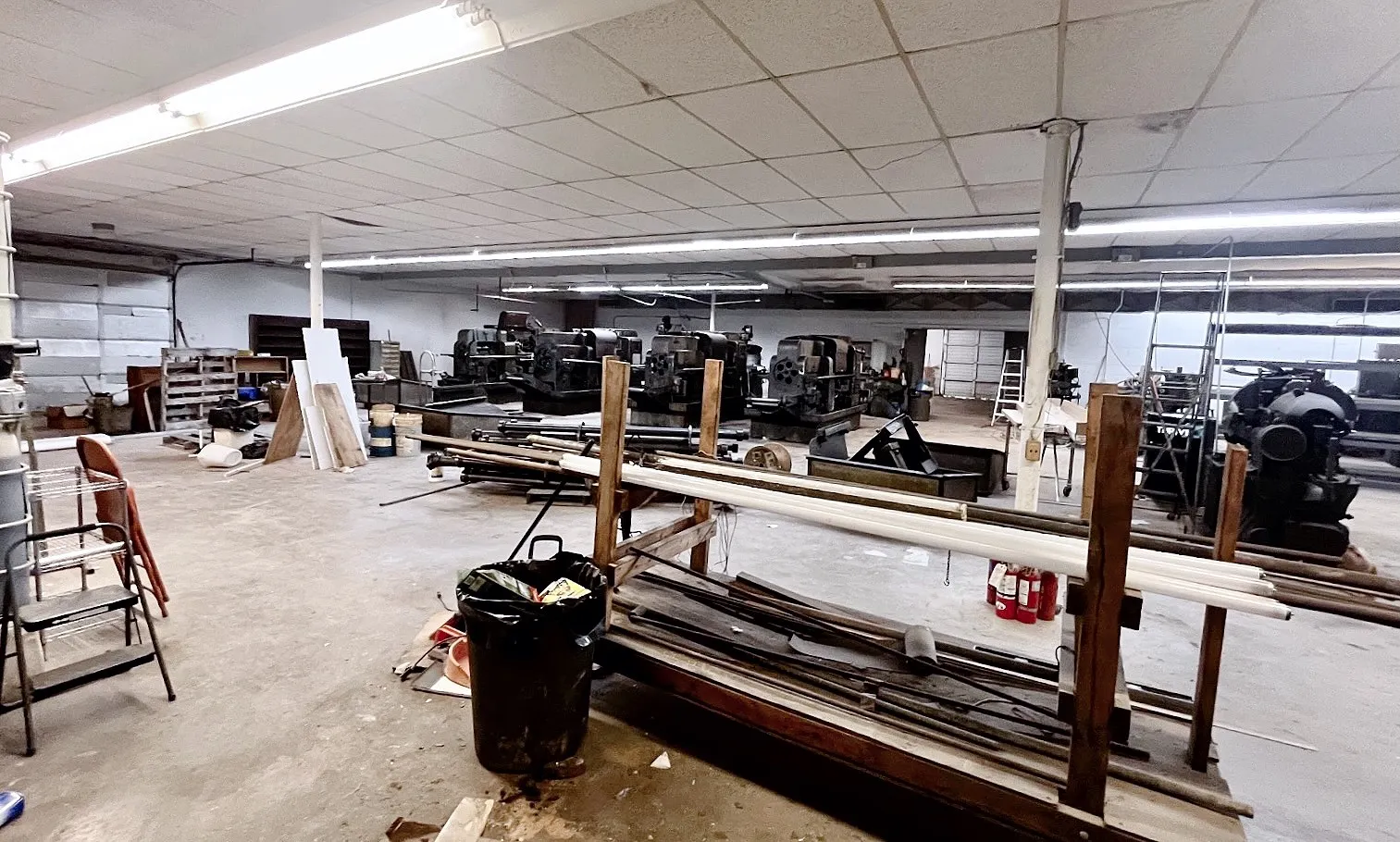 Spacious commercial interior featuring a concrete floor, drop ceiling, and fluorescent lighting