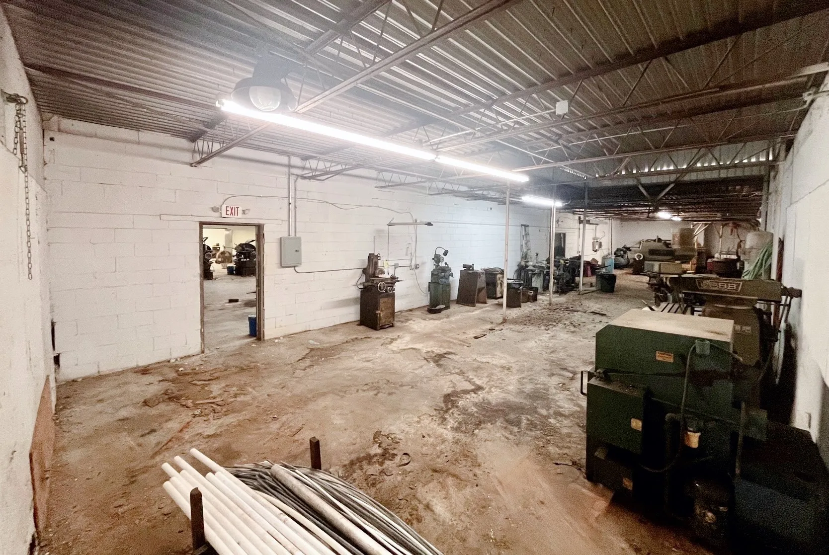 Spacious industrial interior featuring concrete flooring, white block walls, and a metal truss ceiling