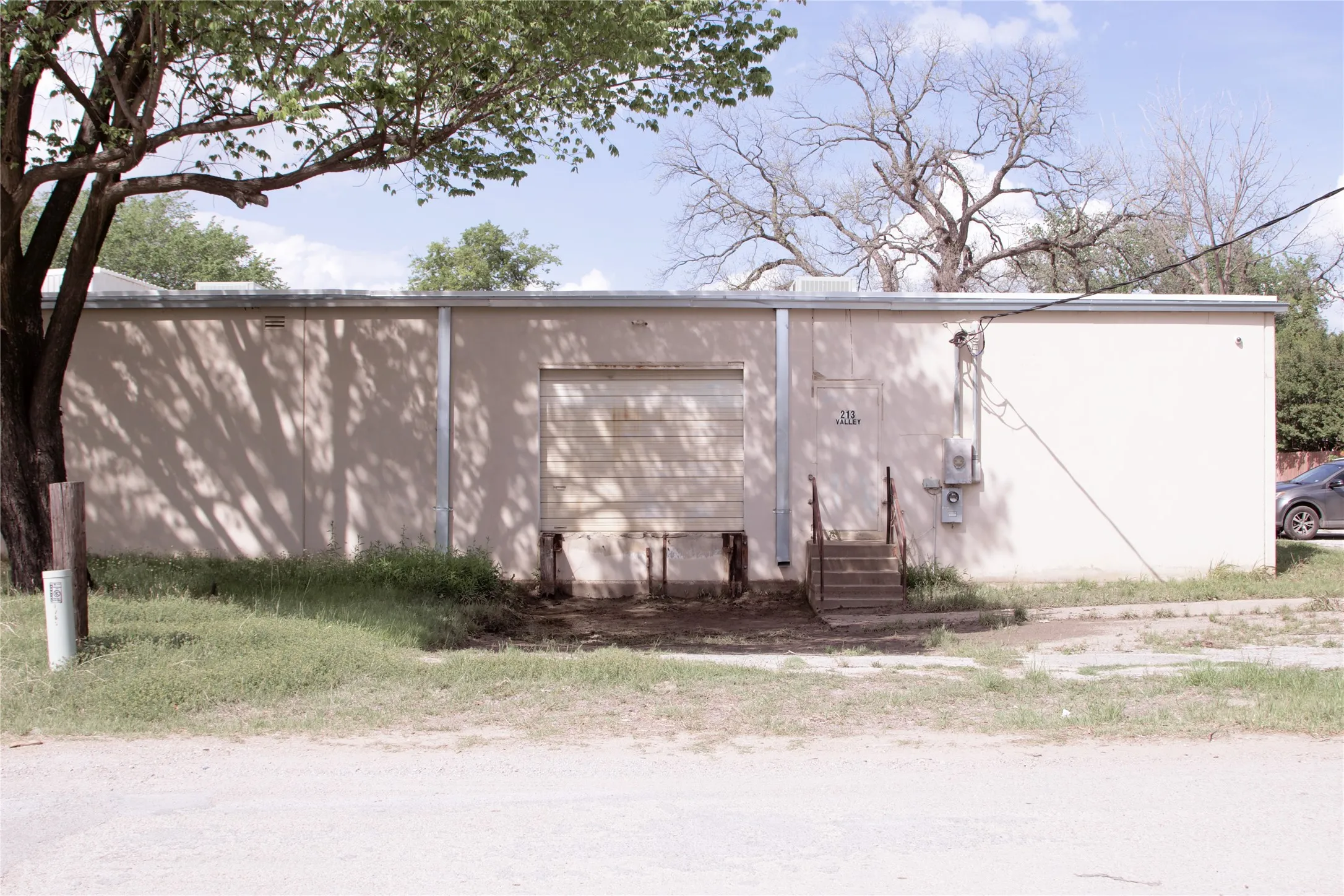 The property features a roll-up garage door and a separate entrance with a concrete staircase