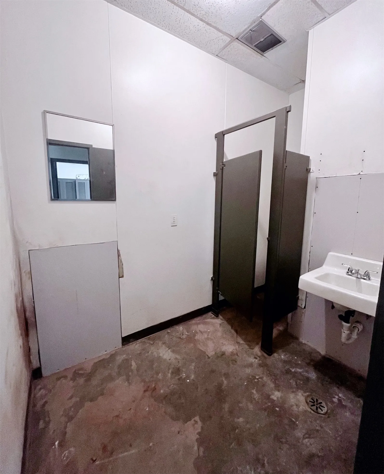 This space features white walls, a white sink, and a drop ceiling