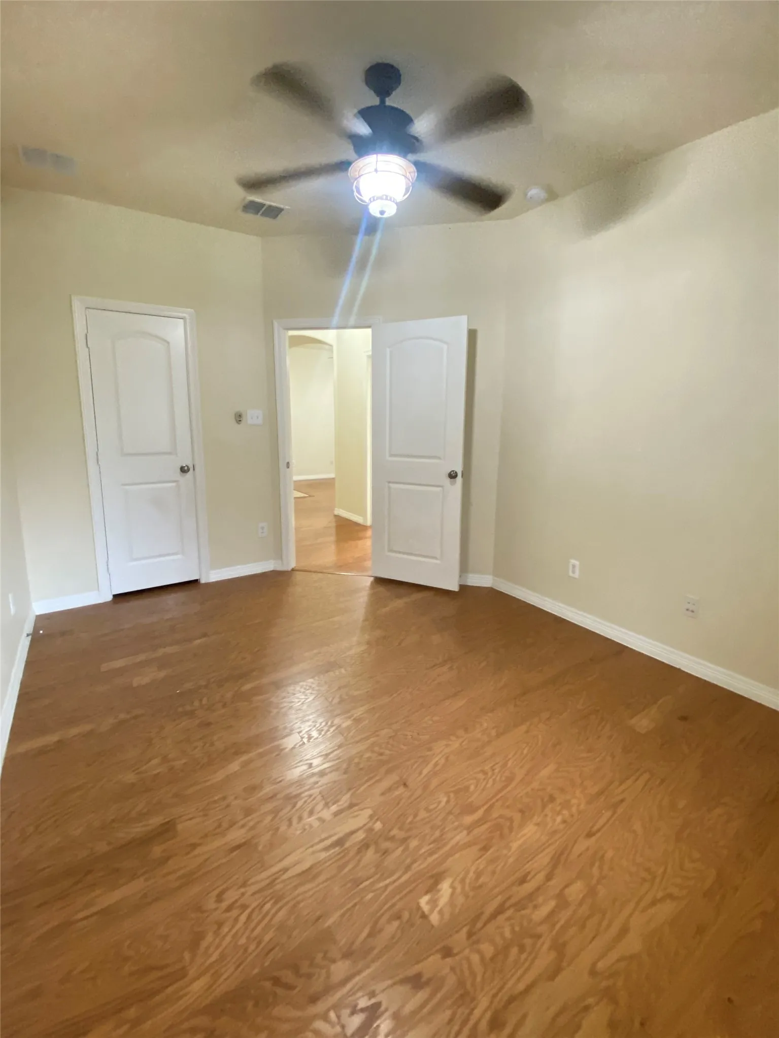 Spacious 3rd bedroom featuring wood-finish flooring, light-toned walls, and a ceiling fan with integrated lighting