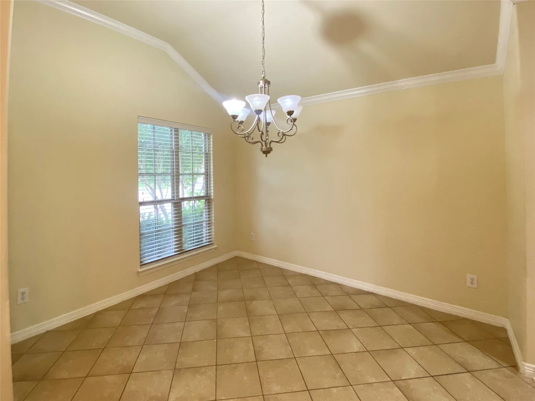 Room featuring vaulted ceiling, crown molding, and a chandelier