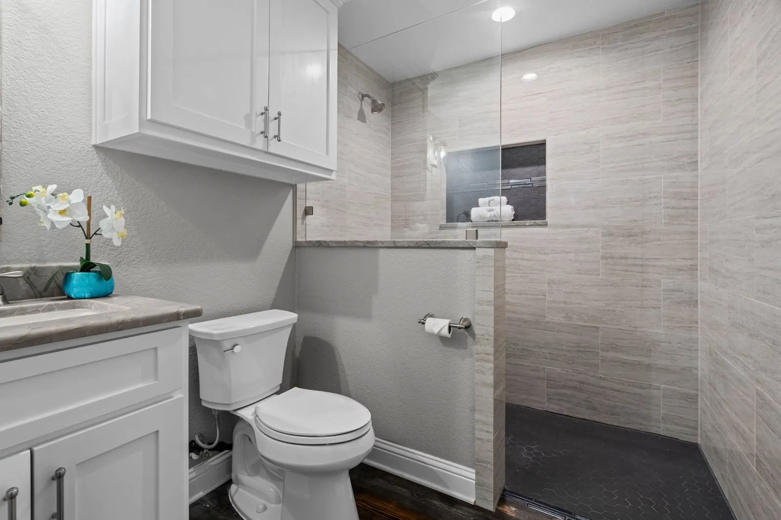 This beautifully finished bathroom features a stylish vanity, a tile-surround walk-in shower with a hex-tile floor, and a clean, modern aesthetic throughout.
