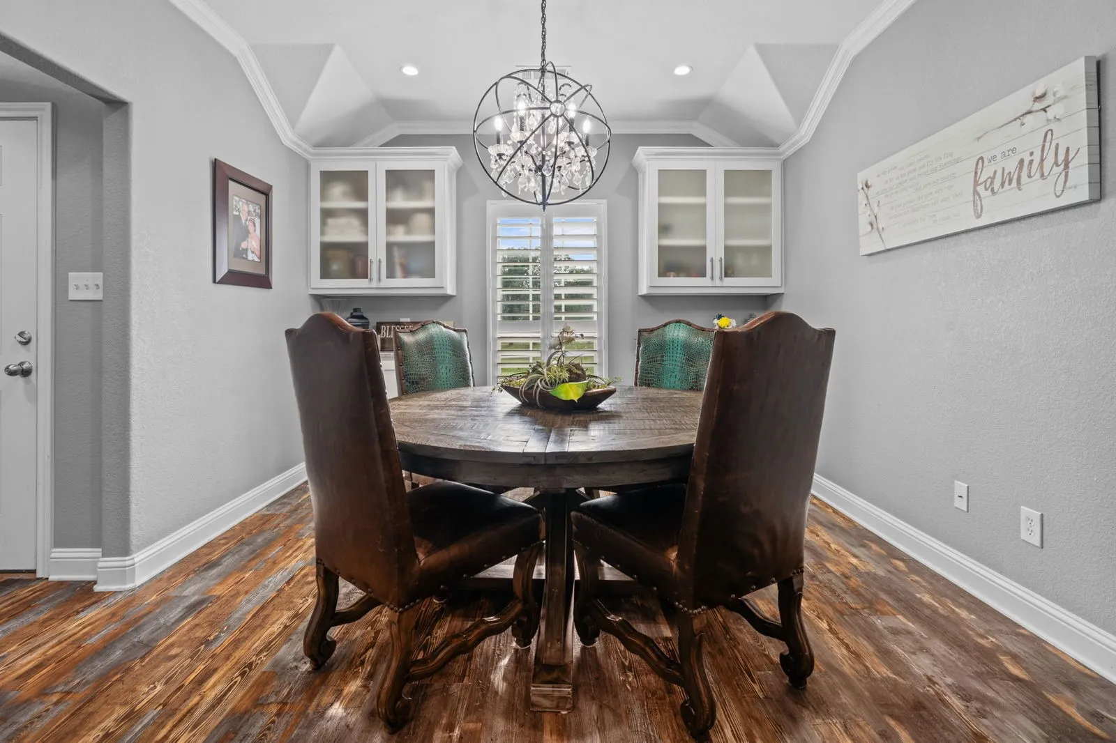 Soft, beautifully blended tones create a warm and welcoming dining space, enhanced by built-ins, a gorgeous chandelier, and warm farmhouse-inspired luxury vinyl floors.