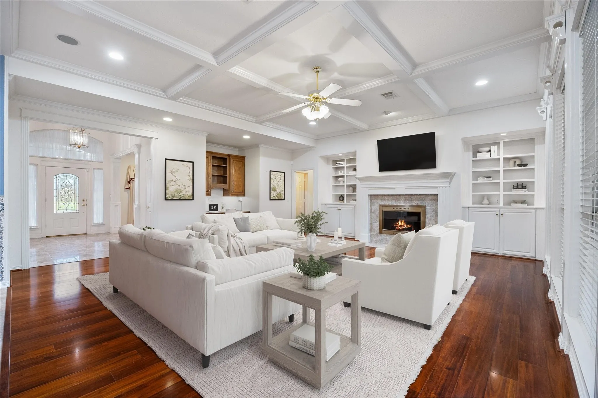 Living area featuring rich hardwood floors, a coffered ceiling, and a fireplace with a light-colored brick surround