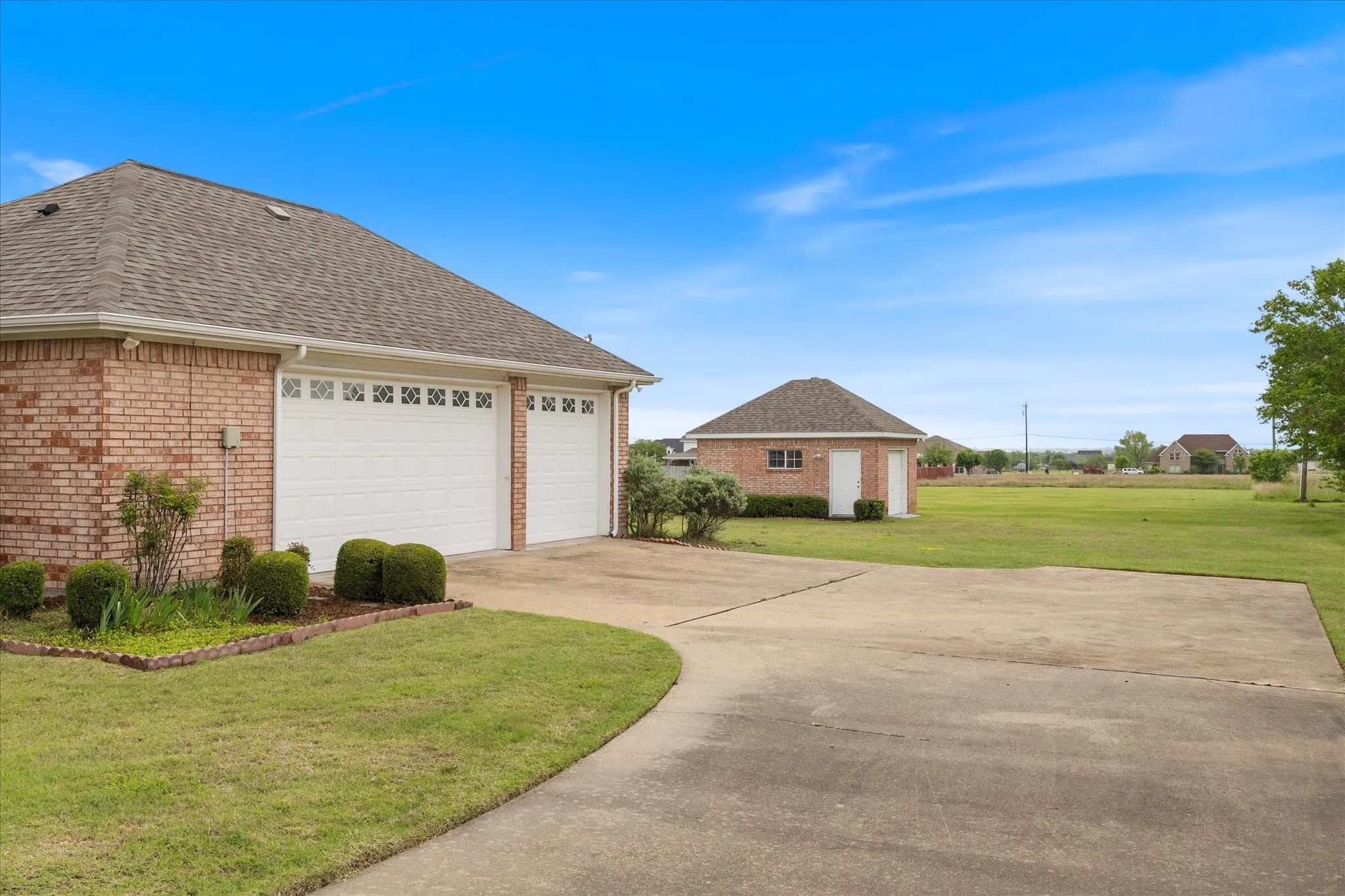 The property features a brick exterior with a multi-car garage, a paved driveway, and an expansive lawn