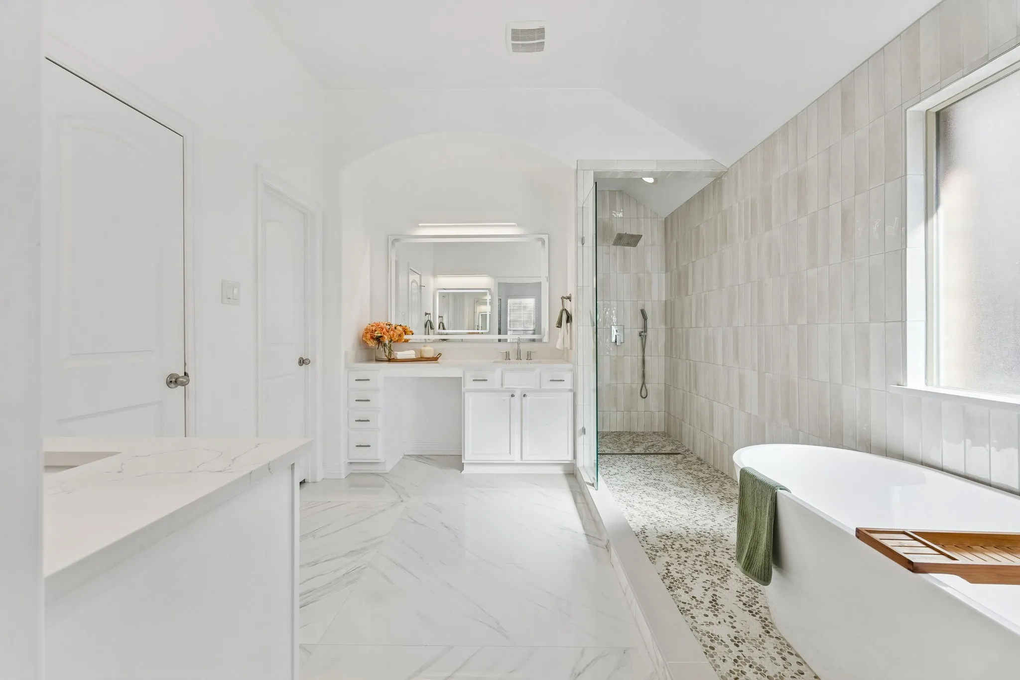 The surprise moment: a spa-style primary bath with soaking tub, oversized shower, LED framed mirrors with temperature control options, and bright elevated finishes.