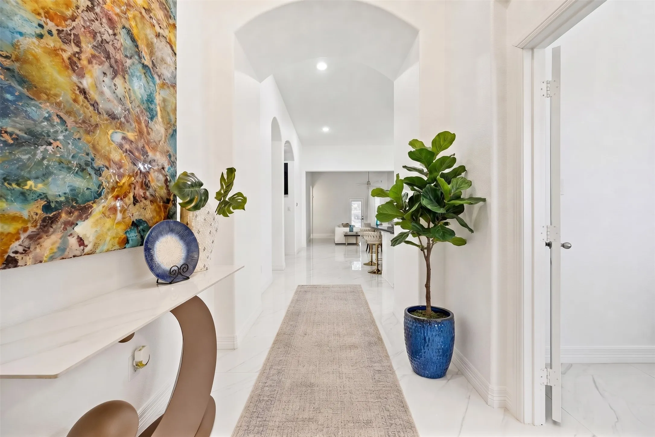 Bright entry with arched hallway, polished porcelain tile, and designer styling that sets the tone for the home.