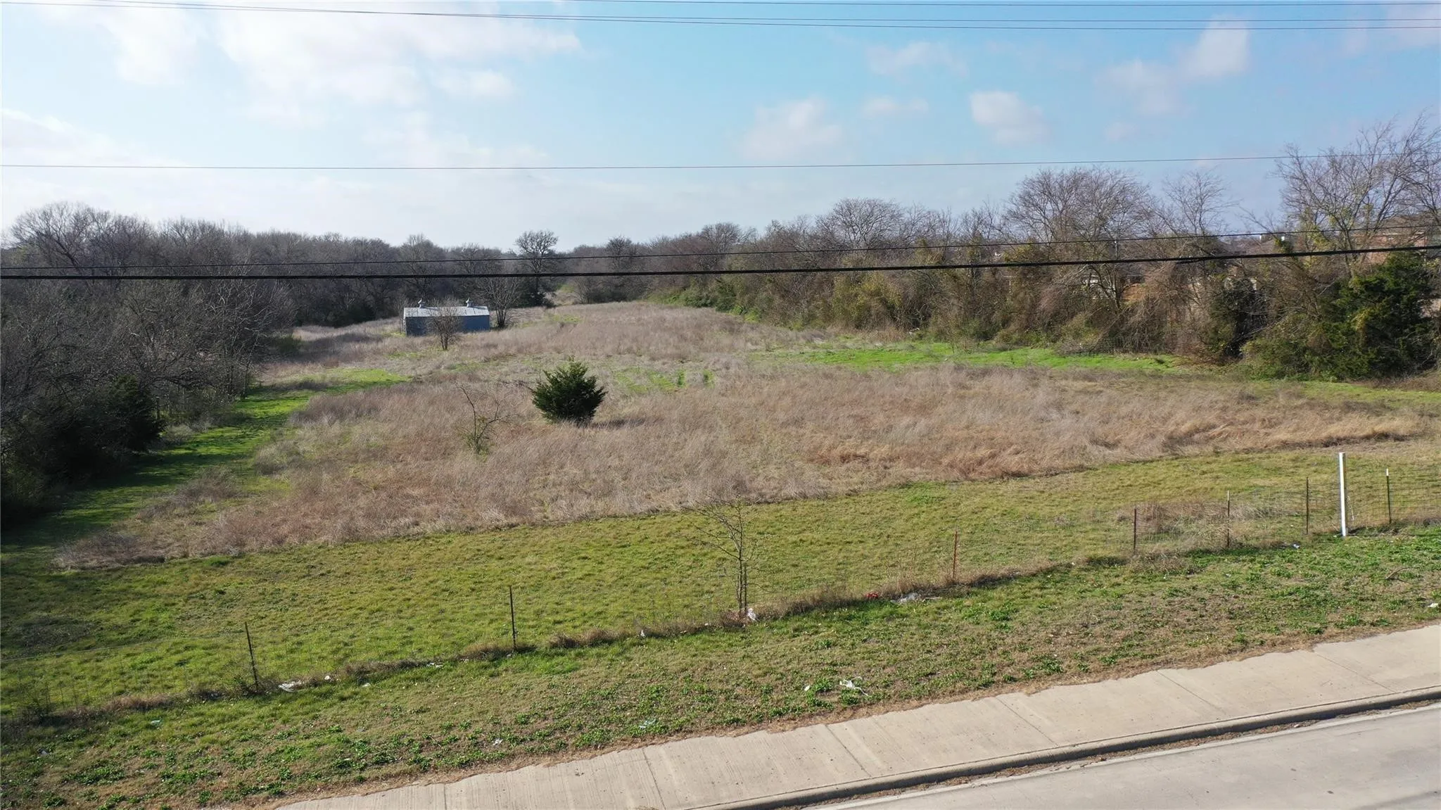 The property offers expansive open land with varying vegetation and a distant structure