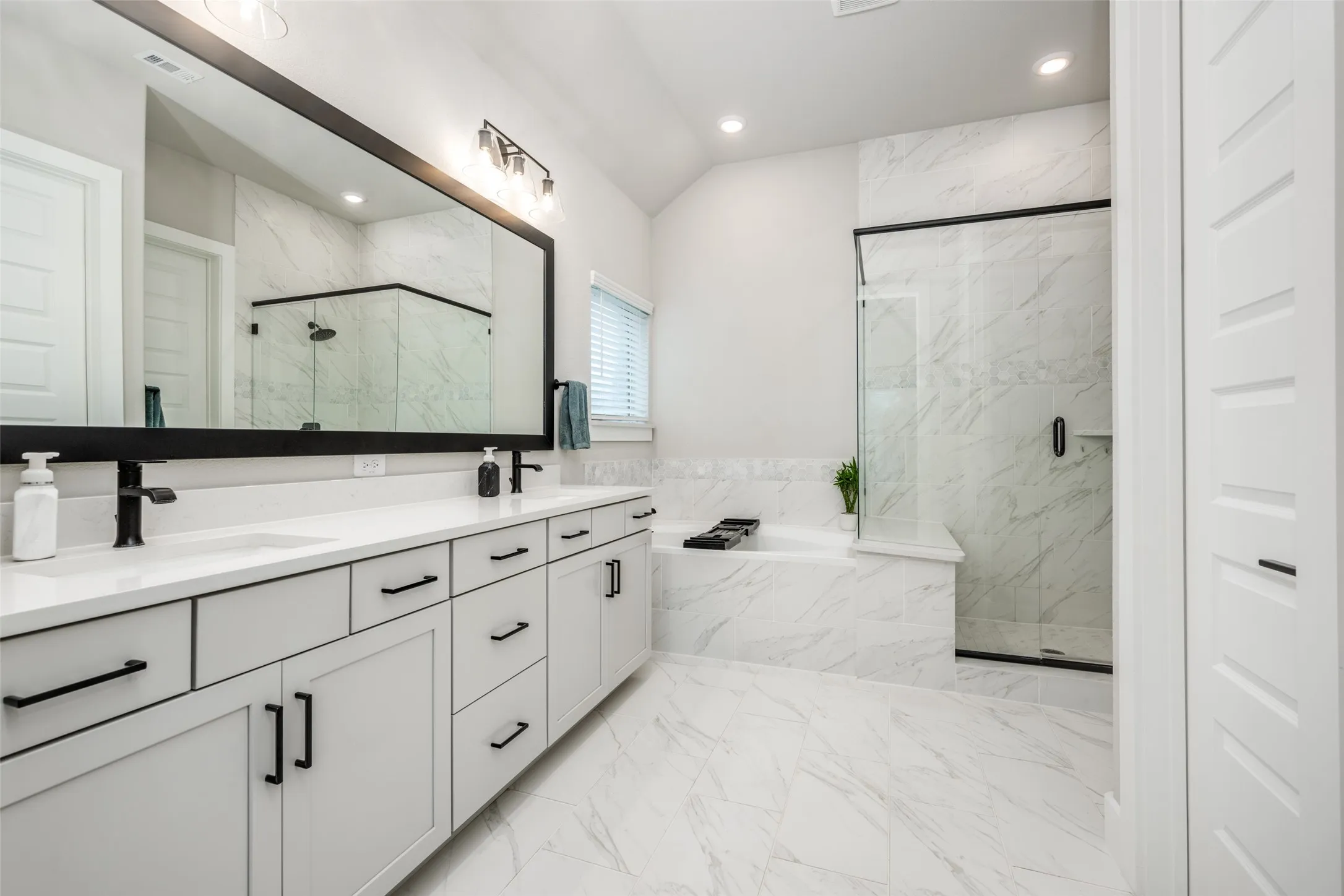 Spacious, sleek, and modern en suite bath with dual sinks, a large garden tub and large shower with bench seat.