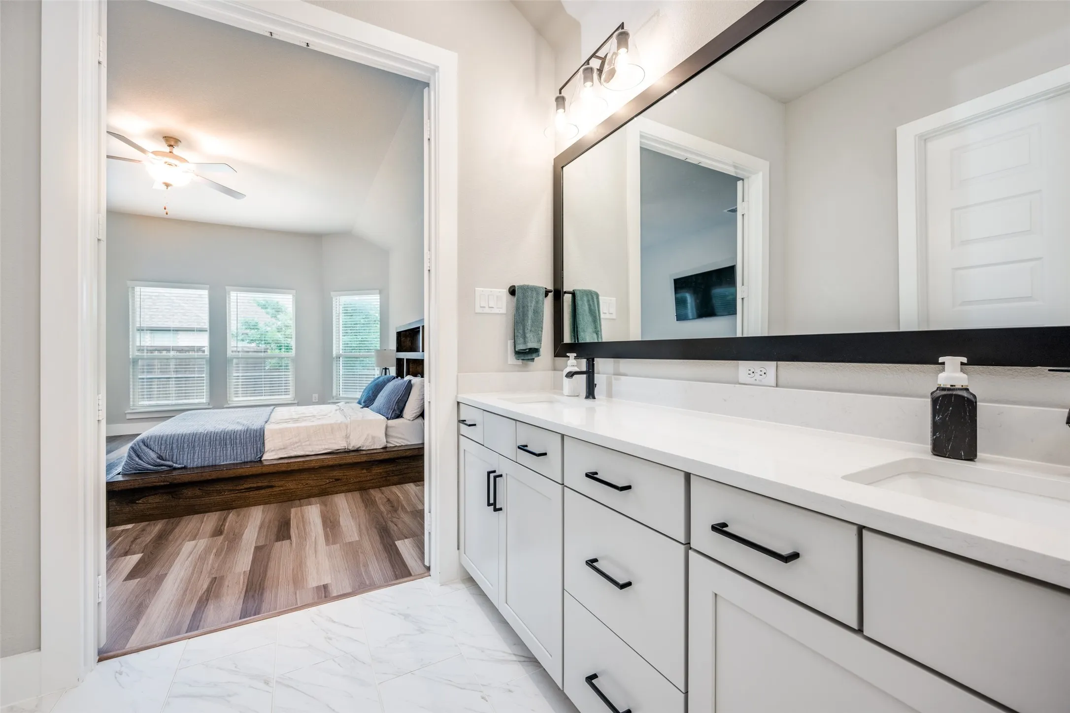 Bathroom featuring a dual vanity with white cabinetry, matte black hardware, and a white countertop