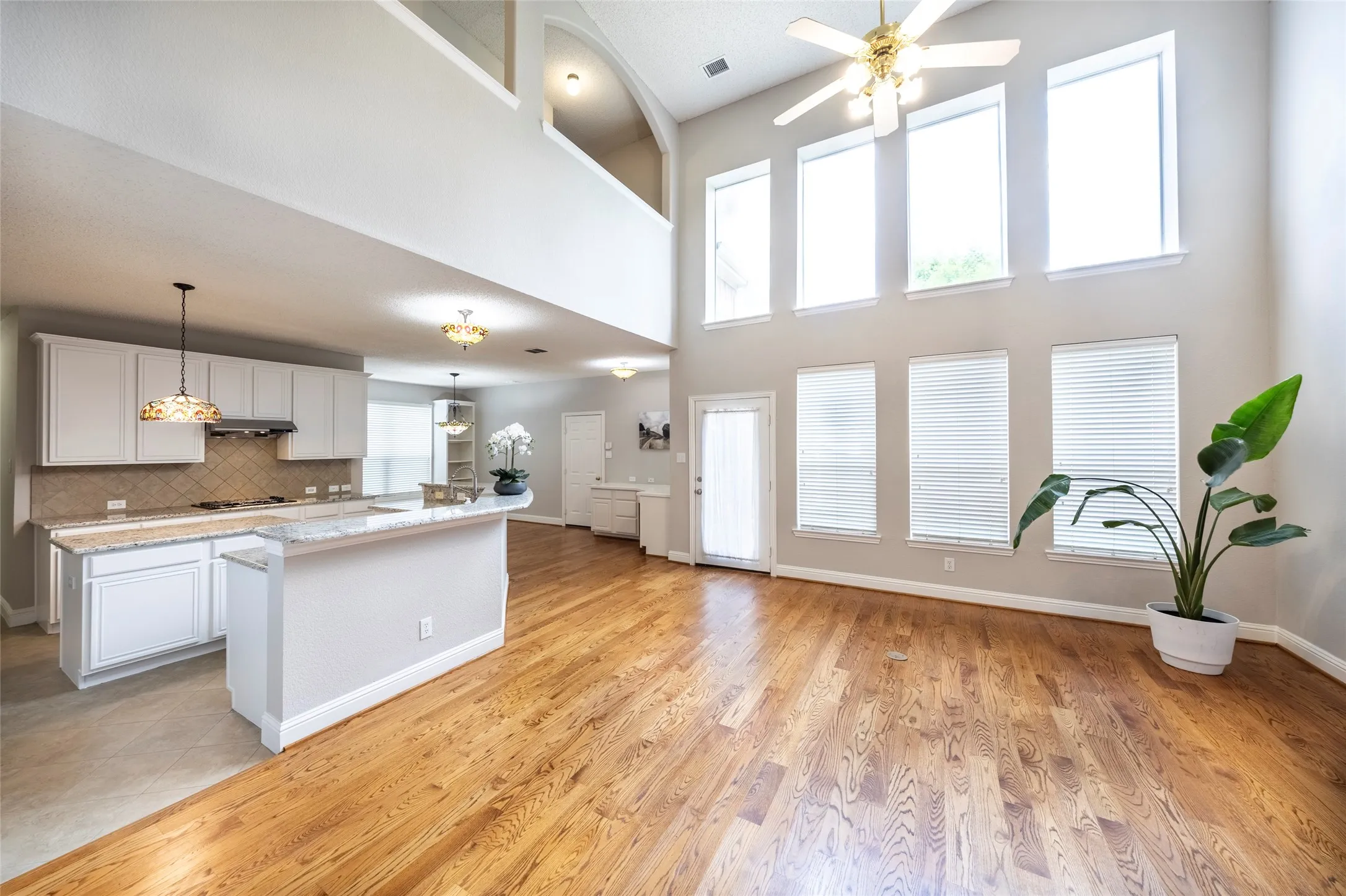 Expansive open-concept living area featuring hardwood flooring, a vaulted ceiling, and large windows providing natural light