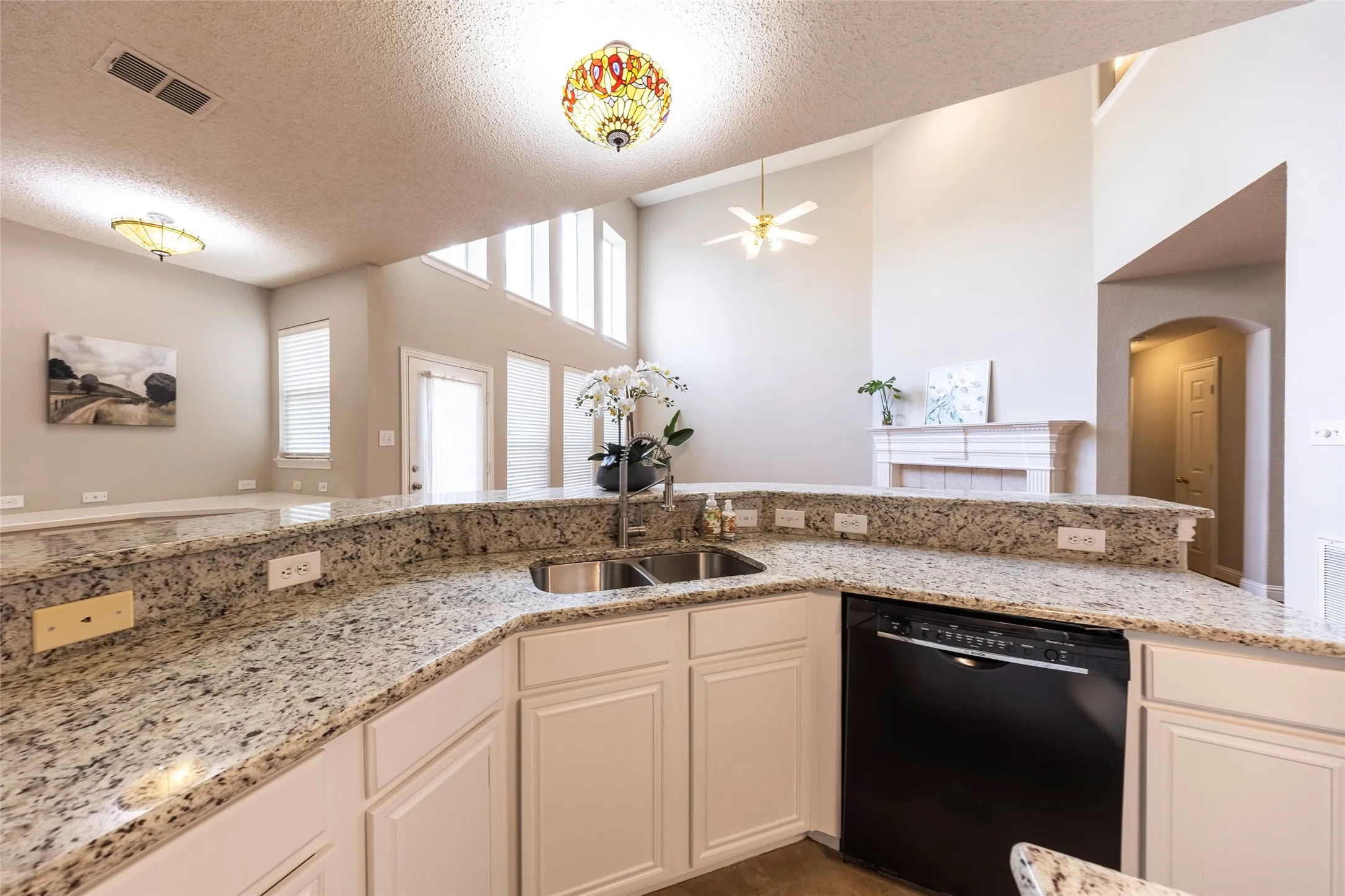 The kitchen features a double basin stainless steel sink, granite countertops, and white cabinetry