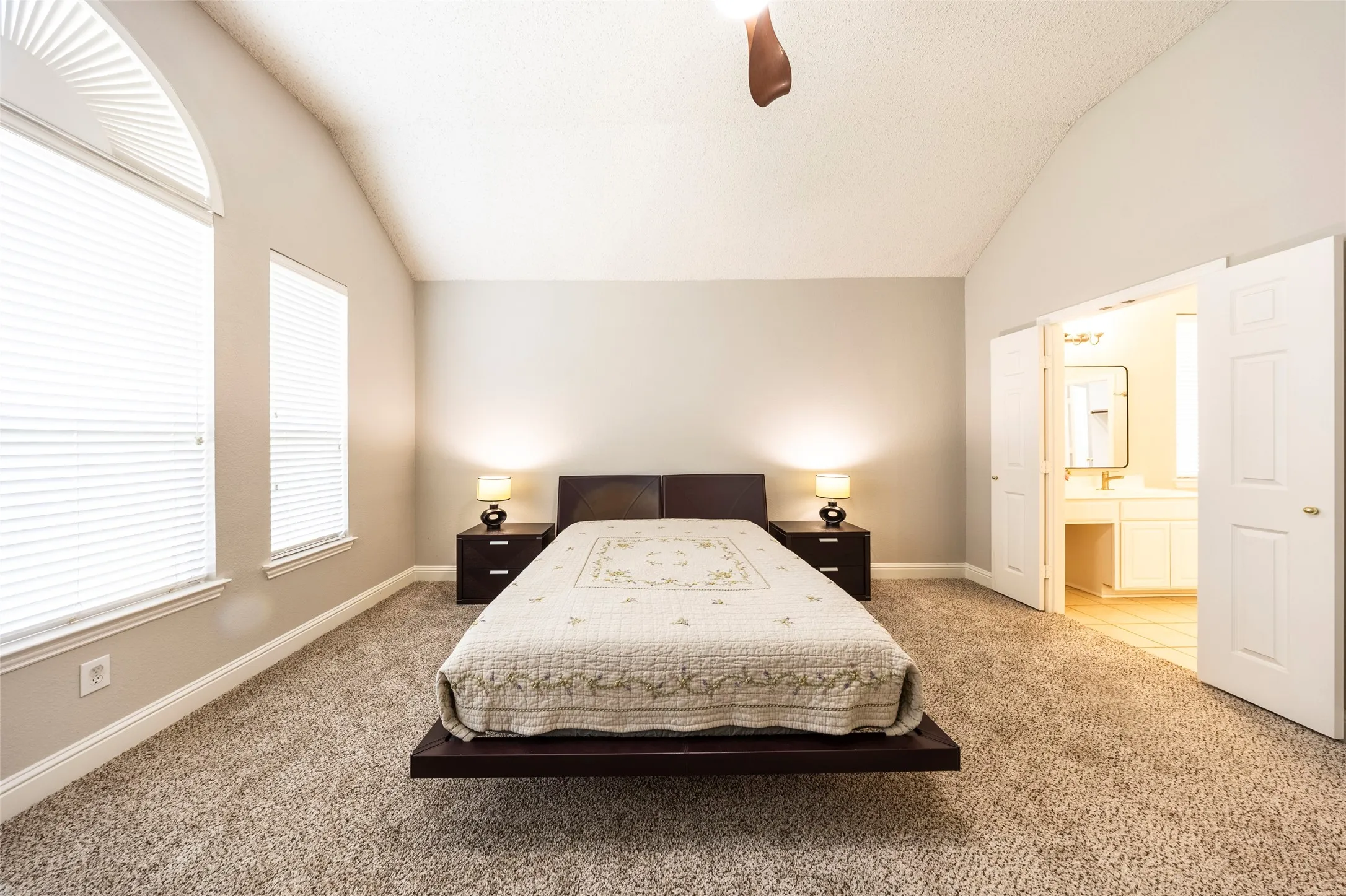 Carpeted room featuring a vaulted ceiling and an arched window