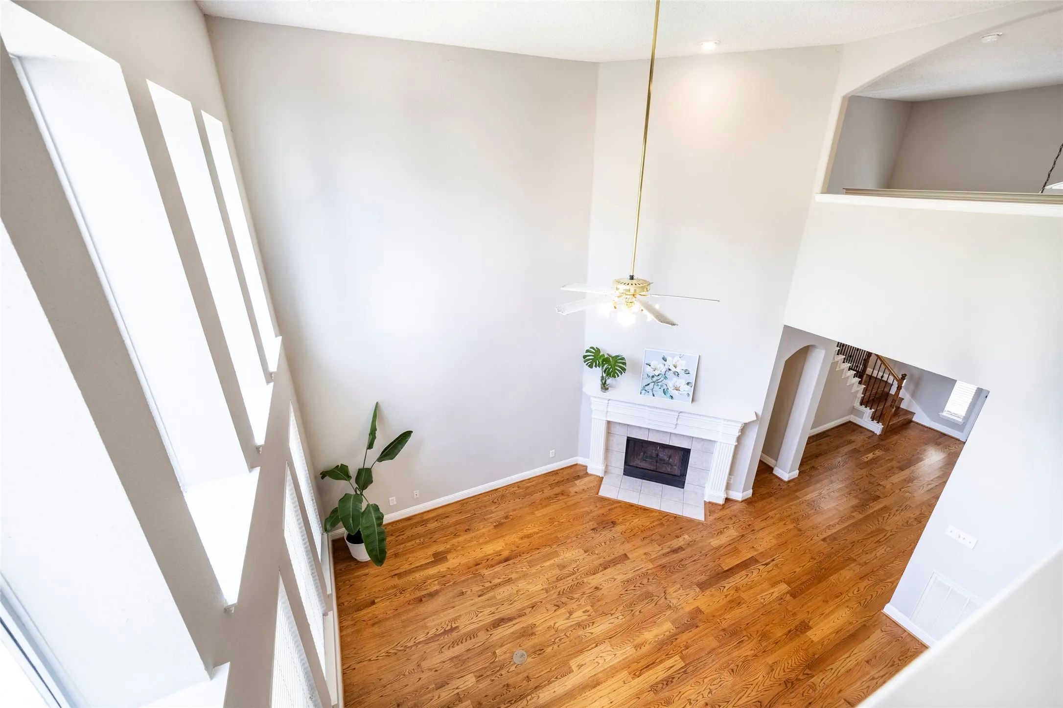 Living area featuring high ceilings, hardwood flooring, a fireplace, and tall windows providing ample natural light