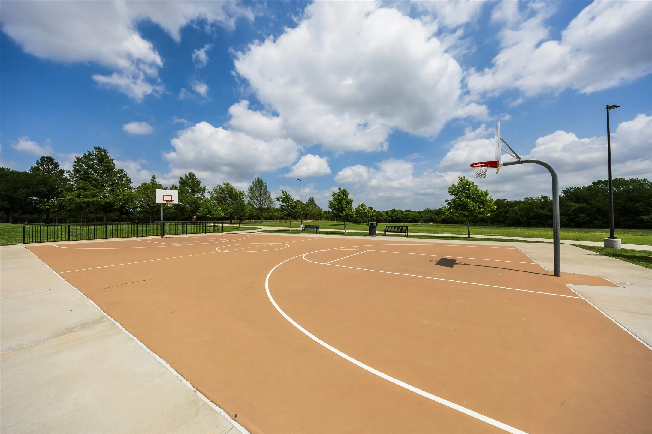 Recreational basketball court featuring a brown surface with white court lines and two hoops