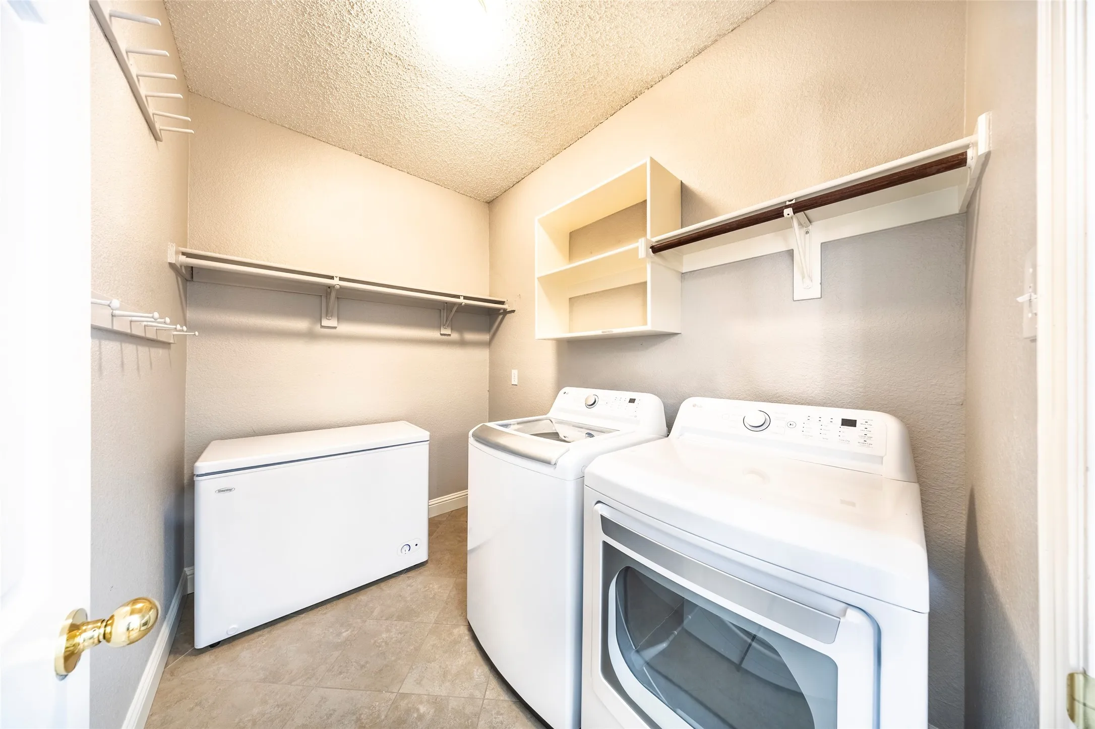 Laundry area featuring tile flooring, built-in shelving, and a hanging rod